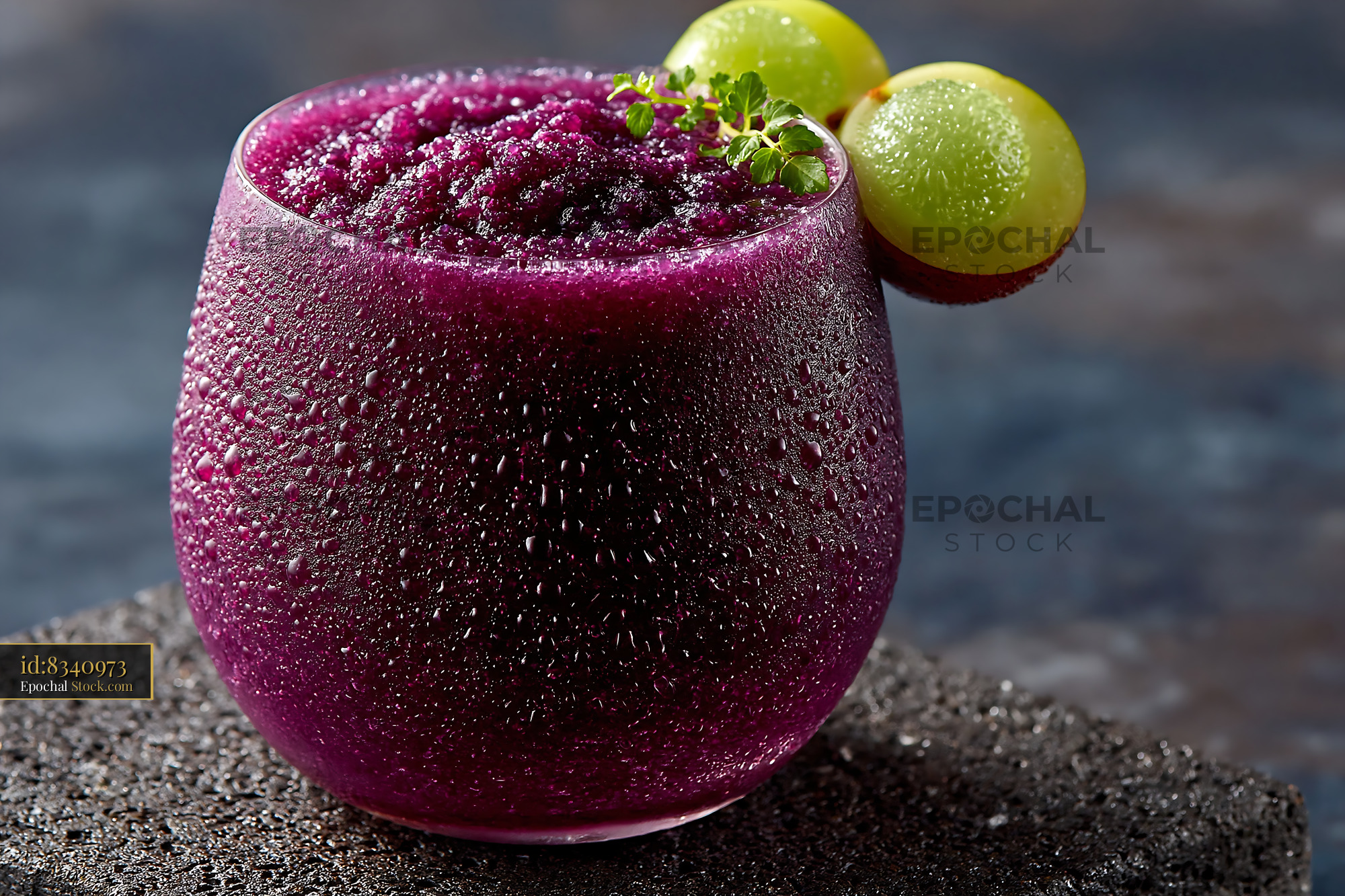 Refreshing purple kyoho grape smoothie with fresh garnish on stone - stock photo