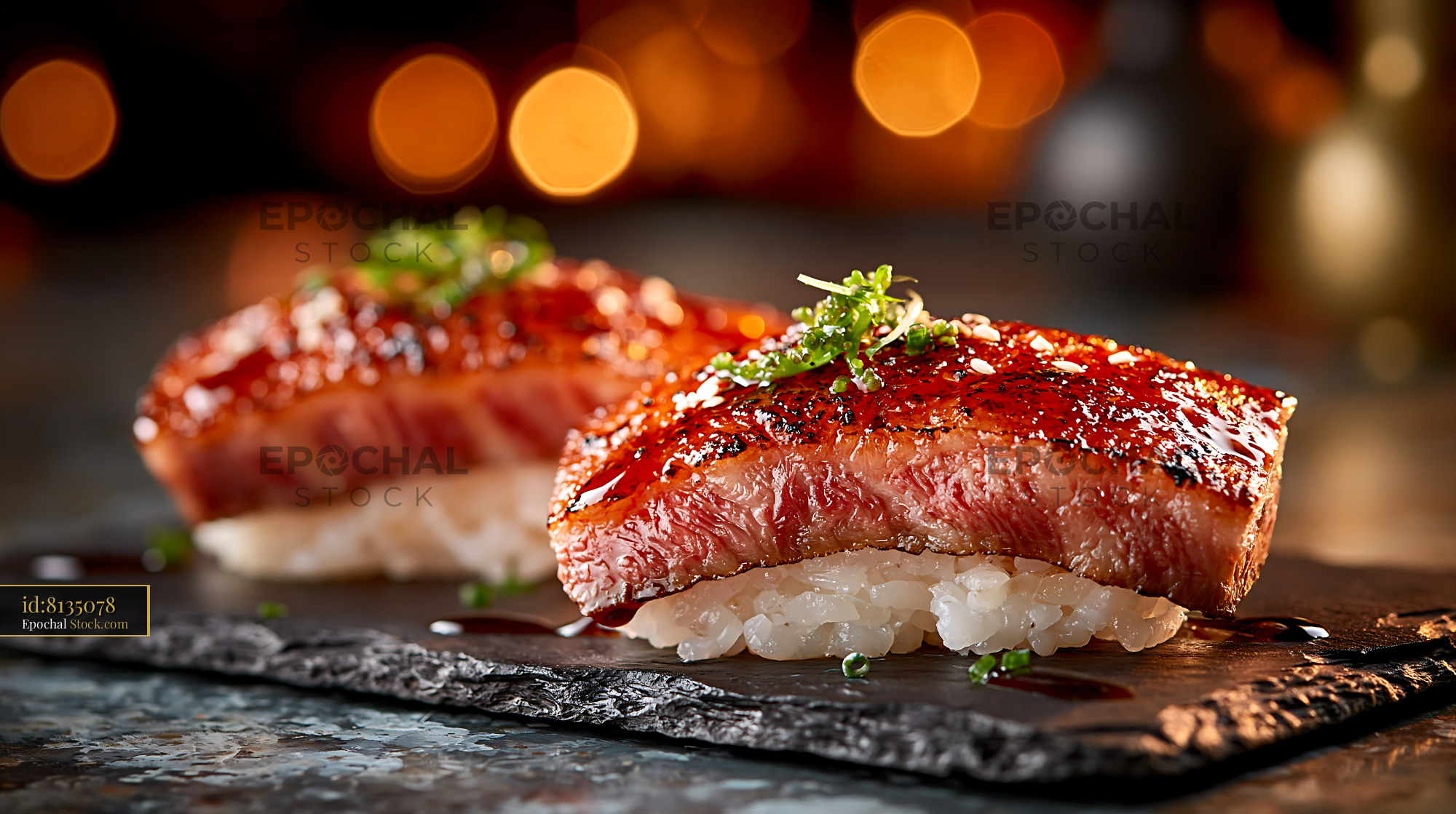 Two pieces of flame seared aburi wagyu sushi on a dark slate plate - stock photo