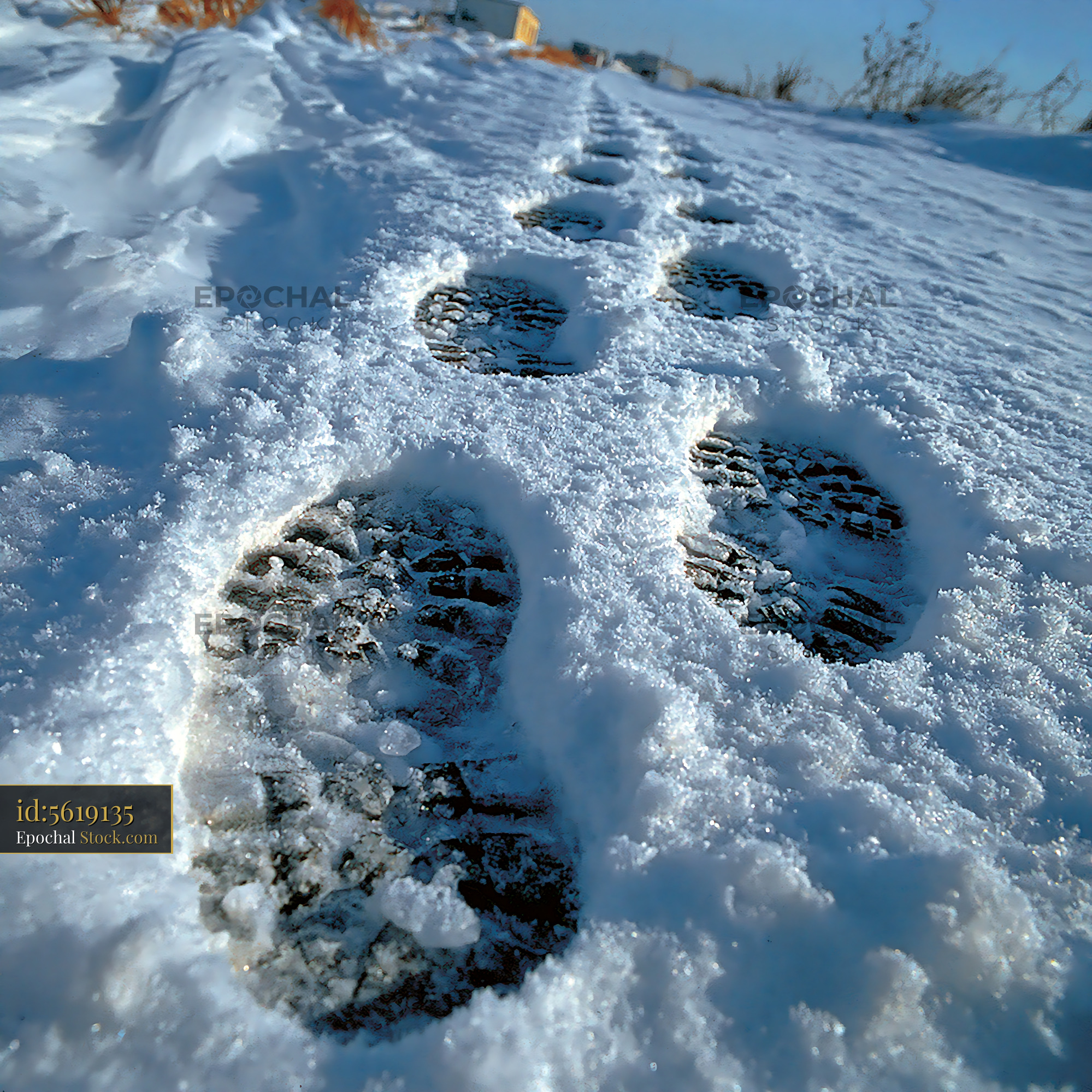 Deep boot prints in fresh snow on a sunny winter day - stock photo