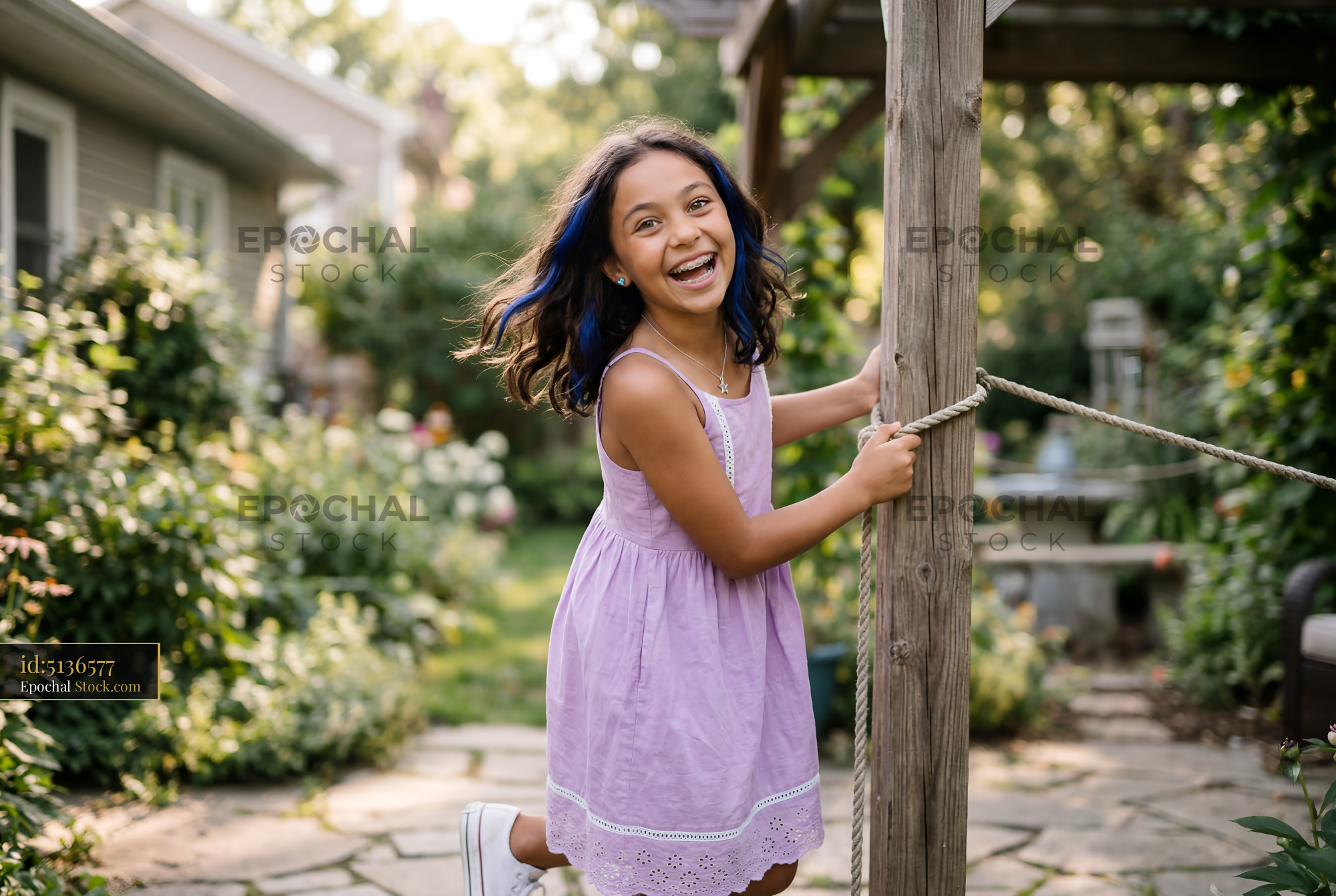 Girl plays on garden swing in sunny backyard in summer Premium Stock Image - stock photo