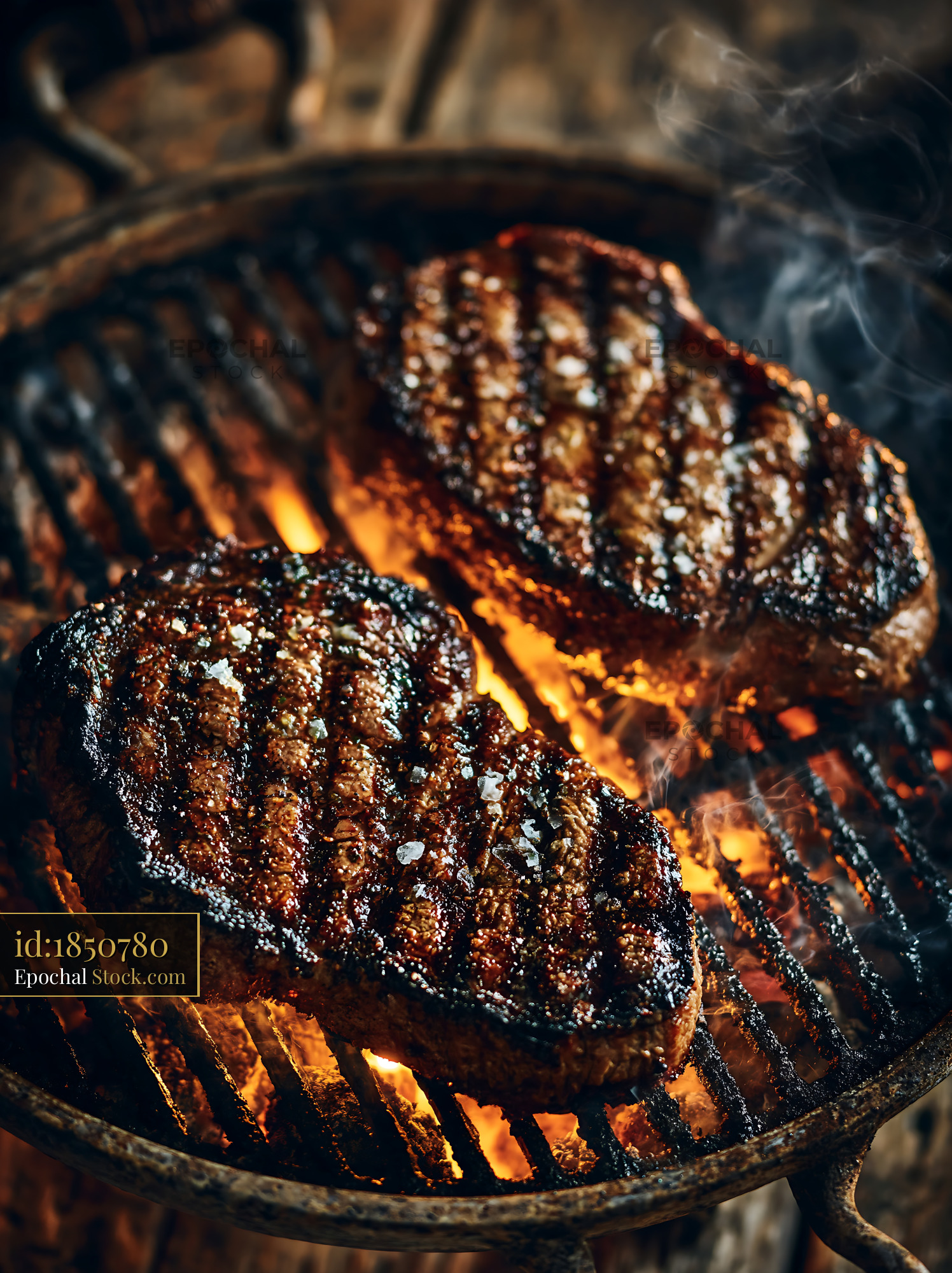 Juicy beef steaks grilling over open flames on a charcoal barbecue - stock photo