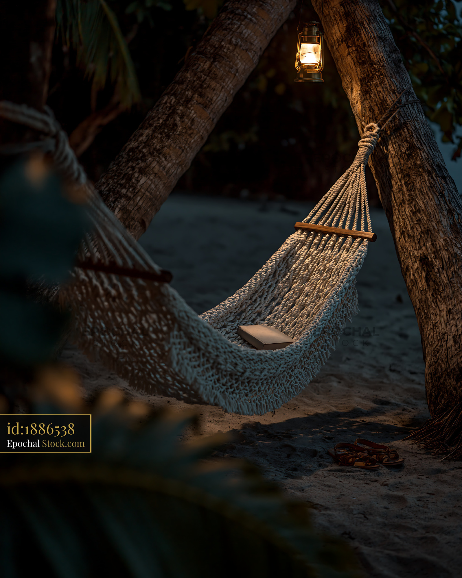 White macrame hammock between palm trees on a beach at night - stock photo