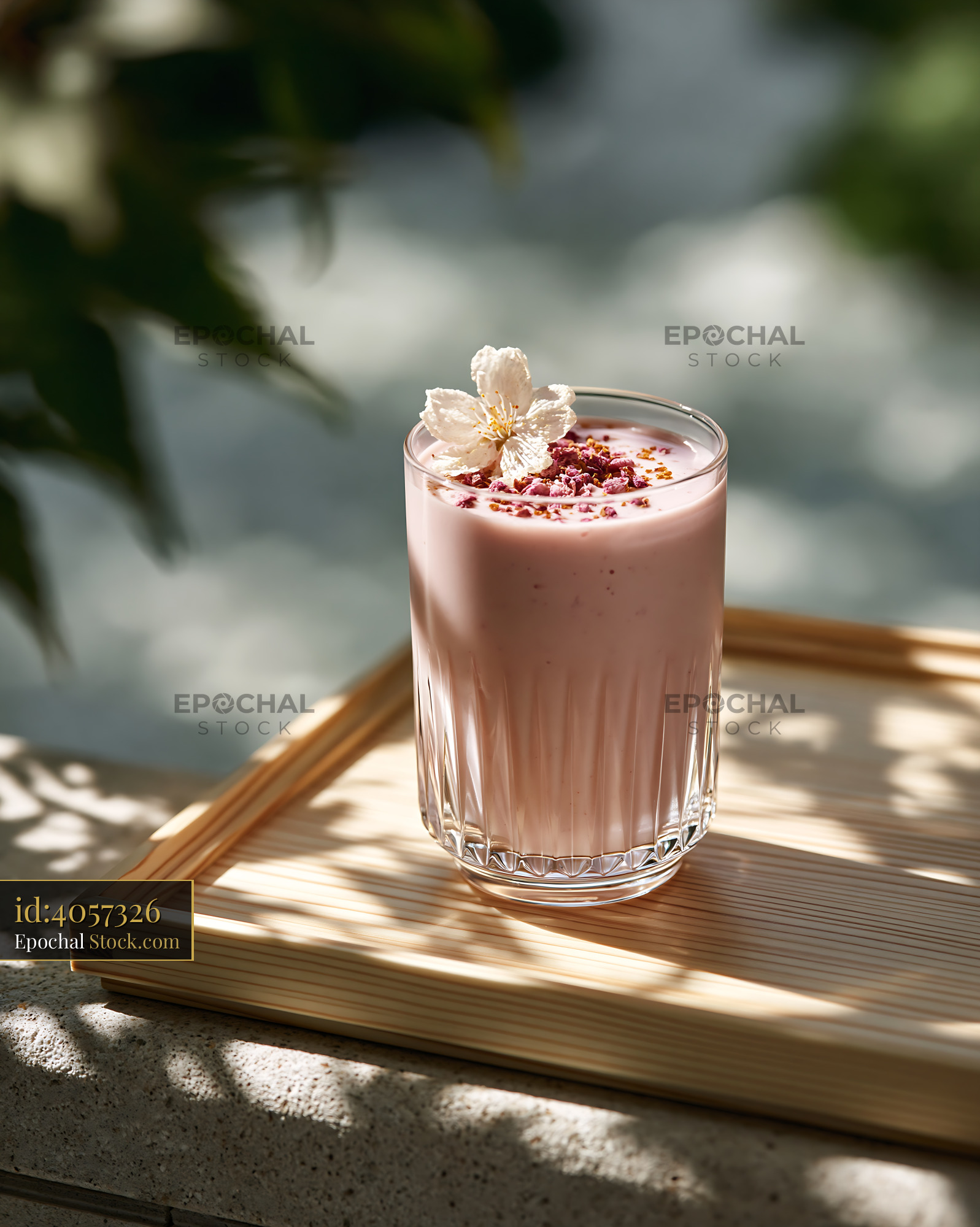 Refreshing sakura blossom smoothie with flower garnish in sunlight - stock photo