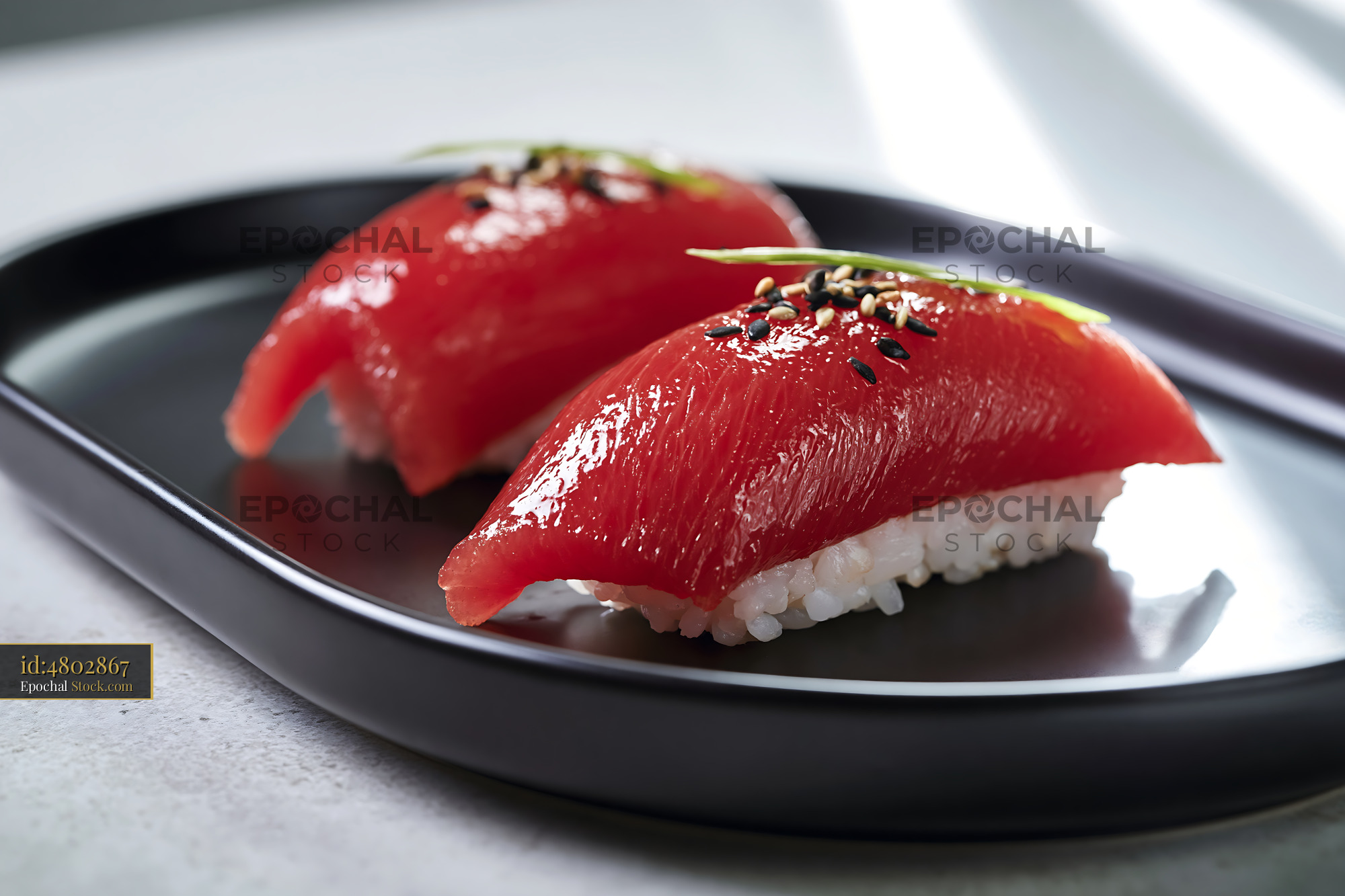 Two pieces of vegan watermelon tuna sushi on a black plate - stock photo