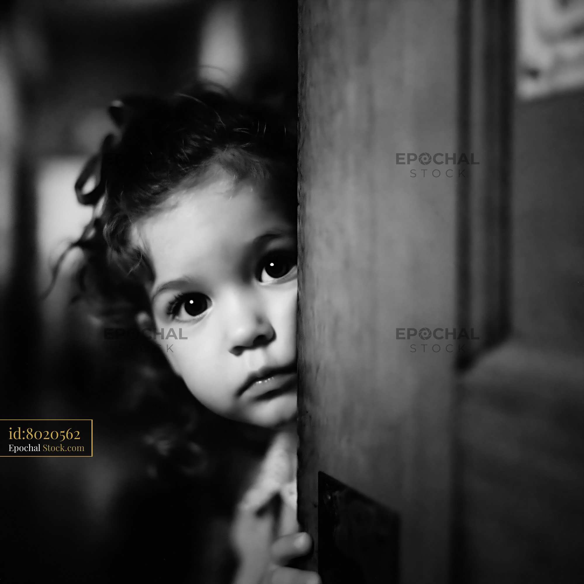 Little girl with curly hair peaking through a classroom door - stock photo