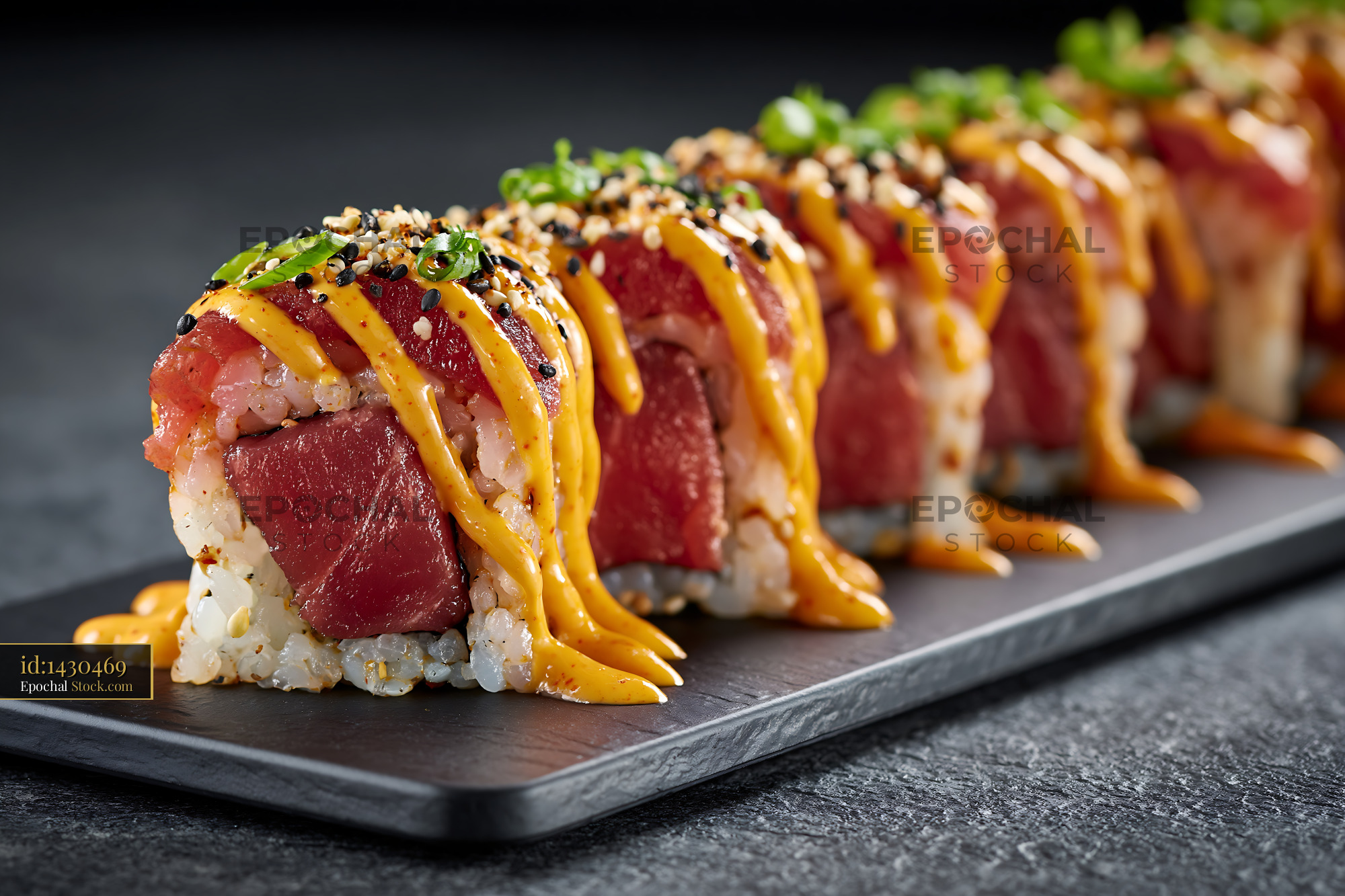 Spicy tuna sushi roll with sriracha mayo and sesame seeds on slate - stock photo