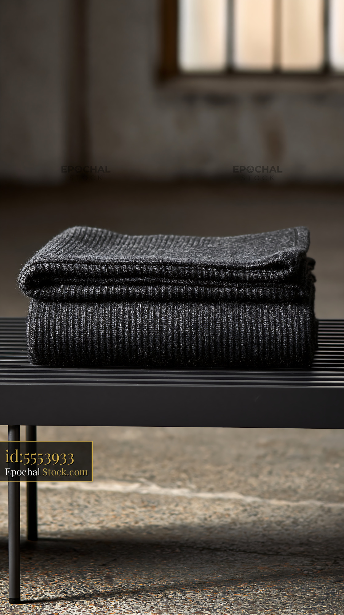 Folded charcoal cashmere throw on a modern black bench - stock photo