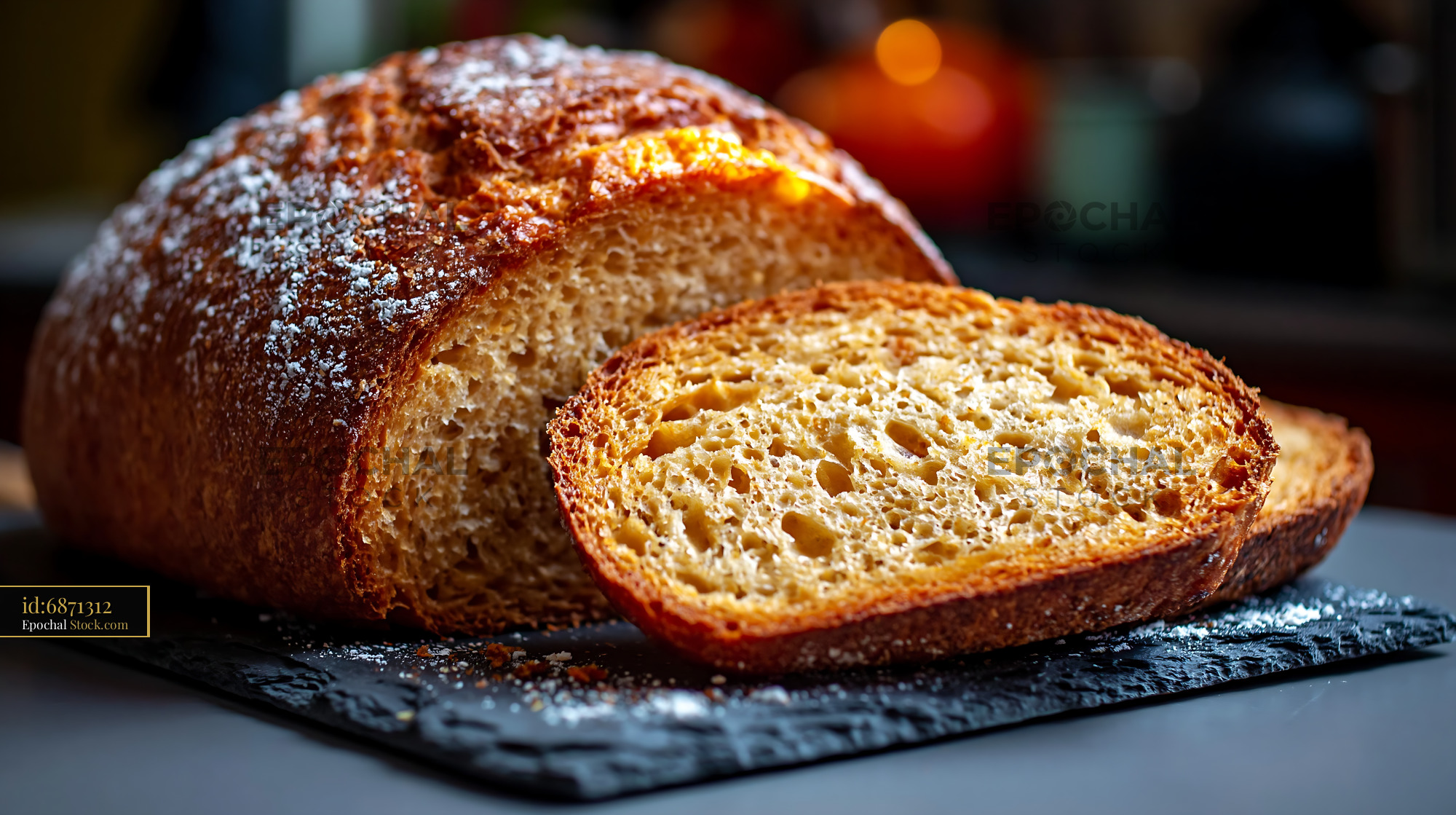 Crusty salt rising german bread loaf sliced on a dark slate board - stock photo