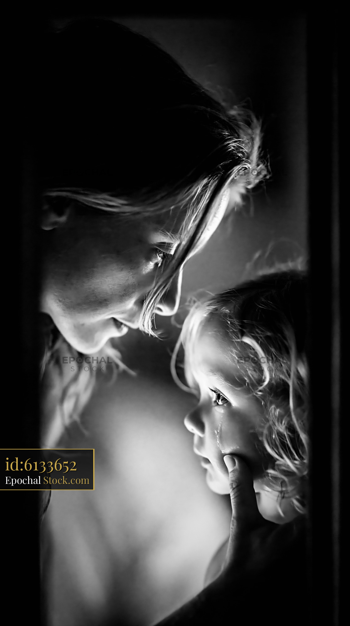 Mother wiping a tear from her young daughter's cheek - stock photo
