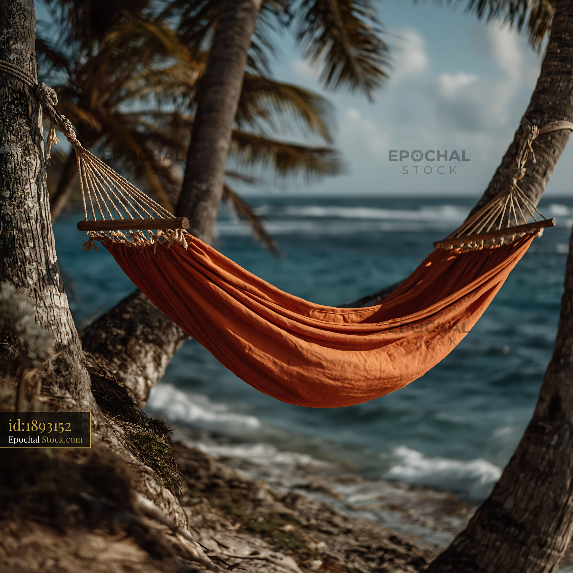 Orange hammock between palm trees on a tropical beach with ocean view - stock photo