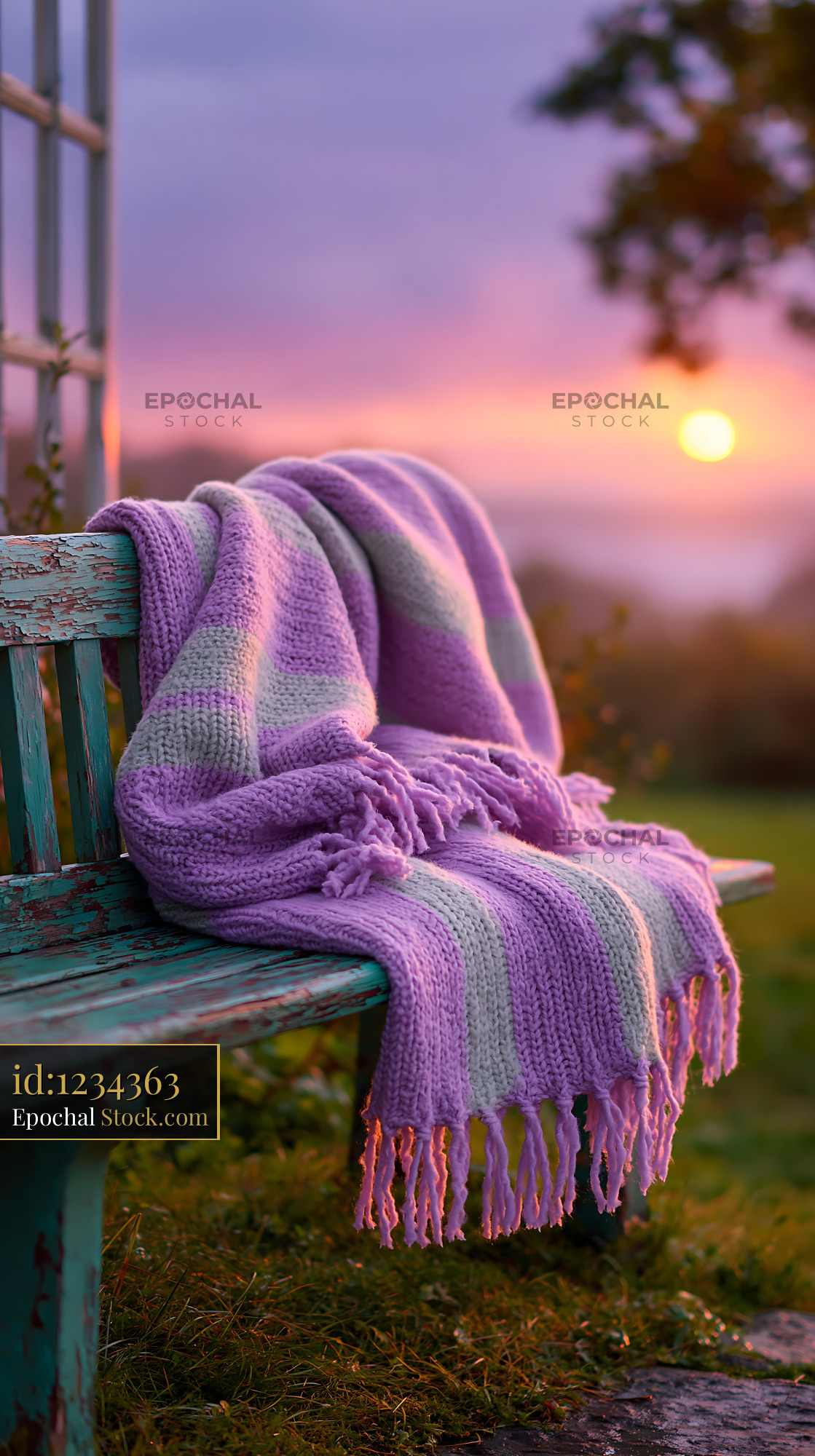 Striped throw on bench in a garden during a purple sunset - stock photo
