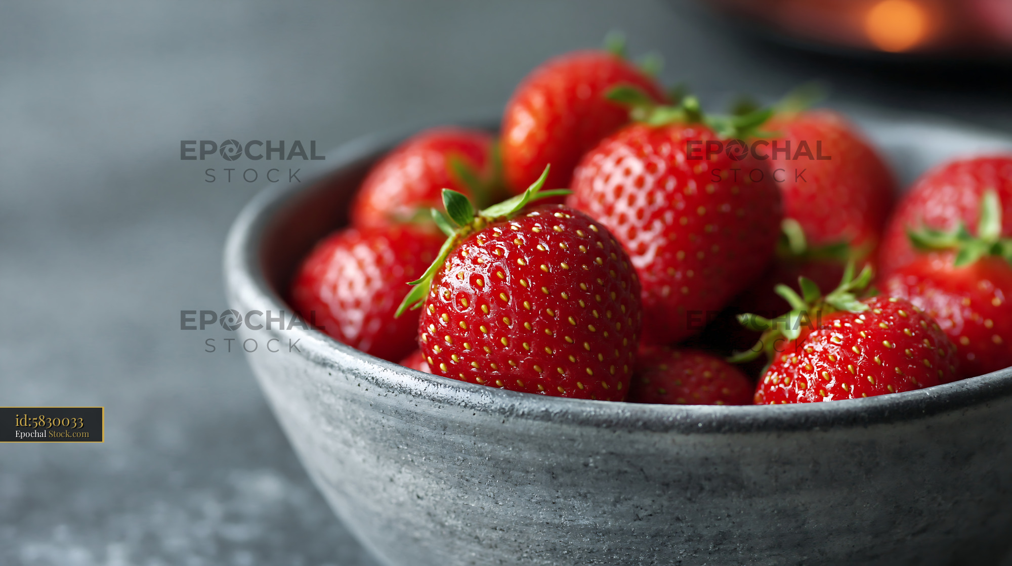 Fresh red strawberries in a grey ceramic bowl on dark stone - stock photo
