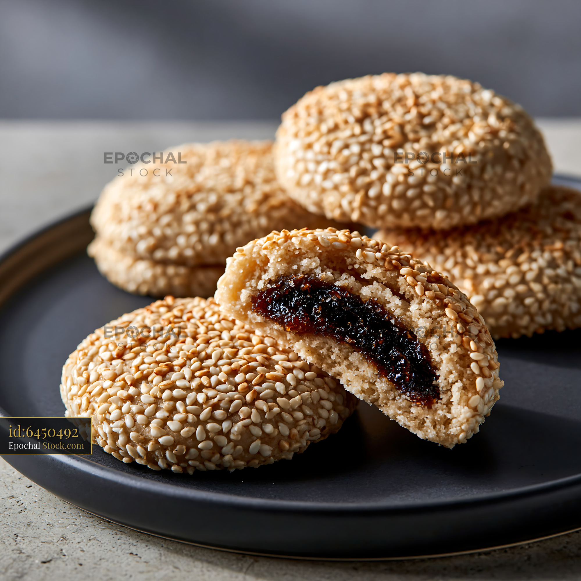 Tahini date biscuits with sesame seeds on a dark plate - stock photo
