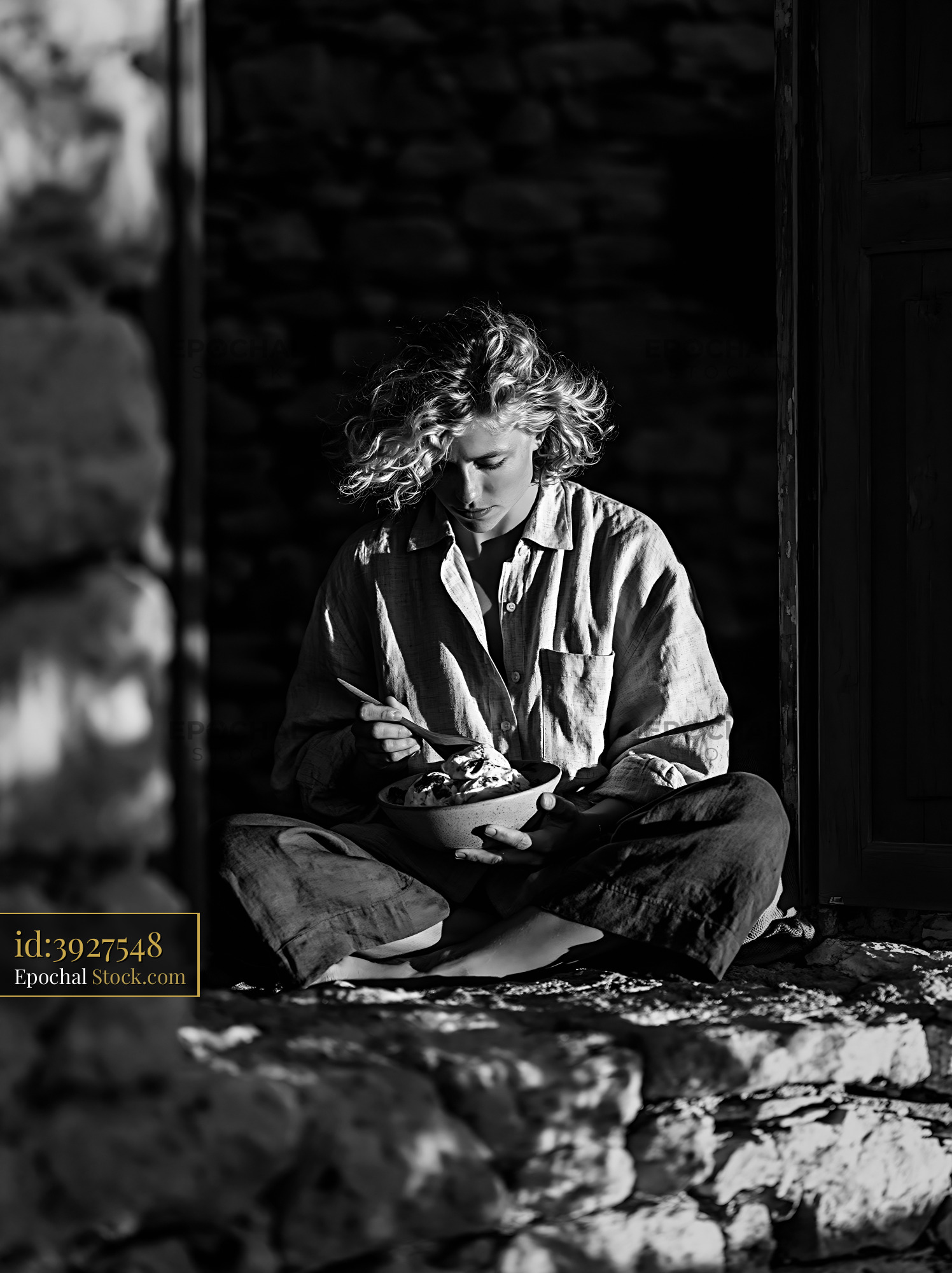 Young woman enjoying fig leaf ice cream in a rustic stone doorway - stock photo