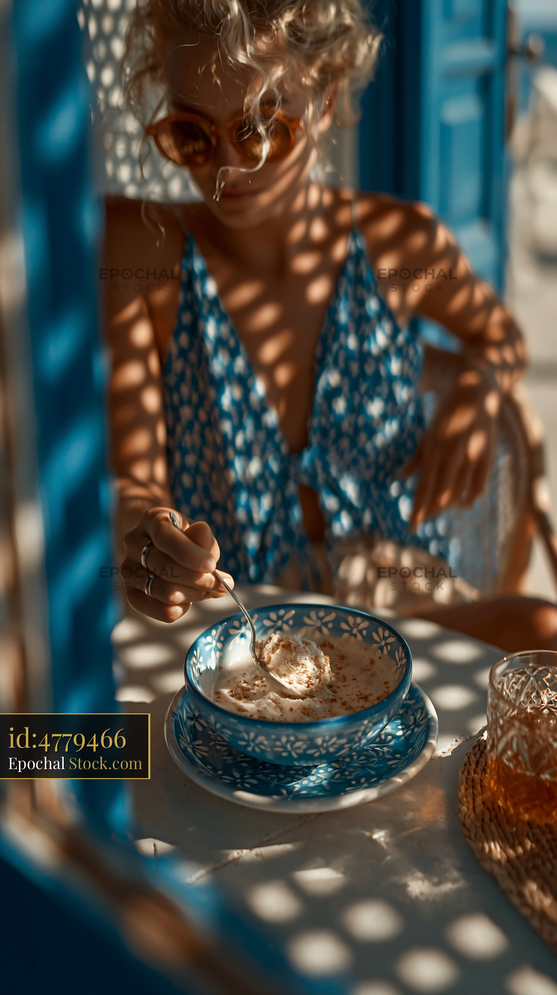 Young woman eating almond paste ice cream at a Mediterranean cafe - stock photo