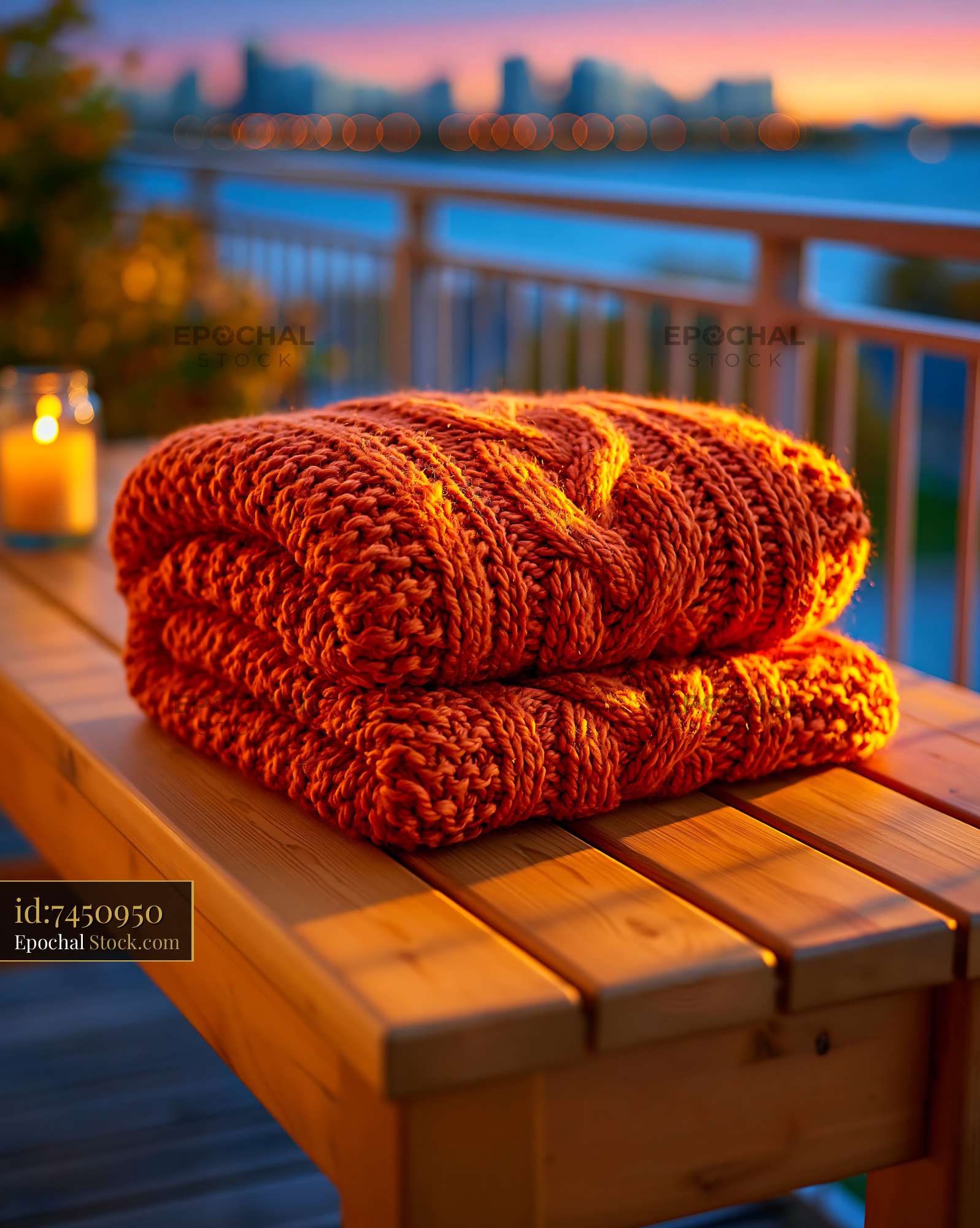 Cozy orange knit throw on a wooden balcony bench at sunset - stock photo