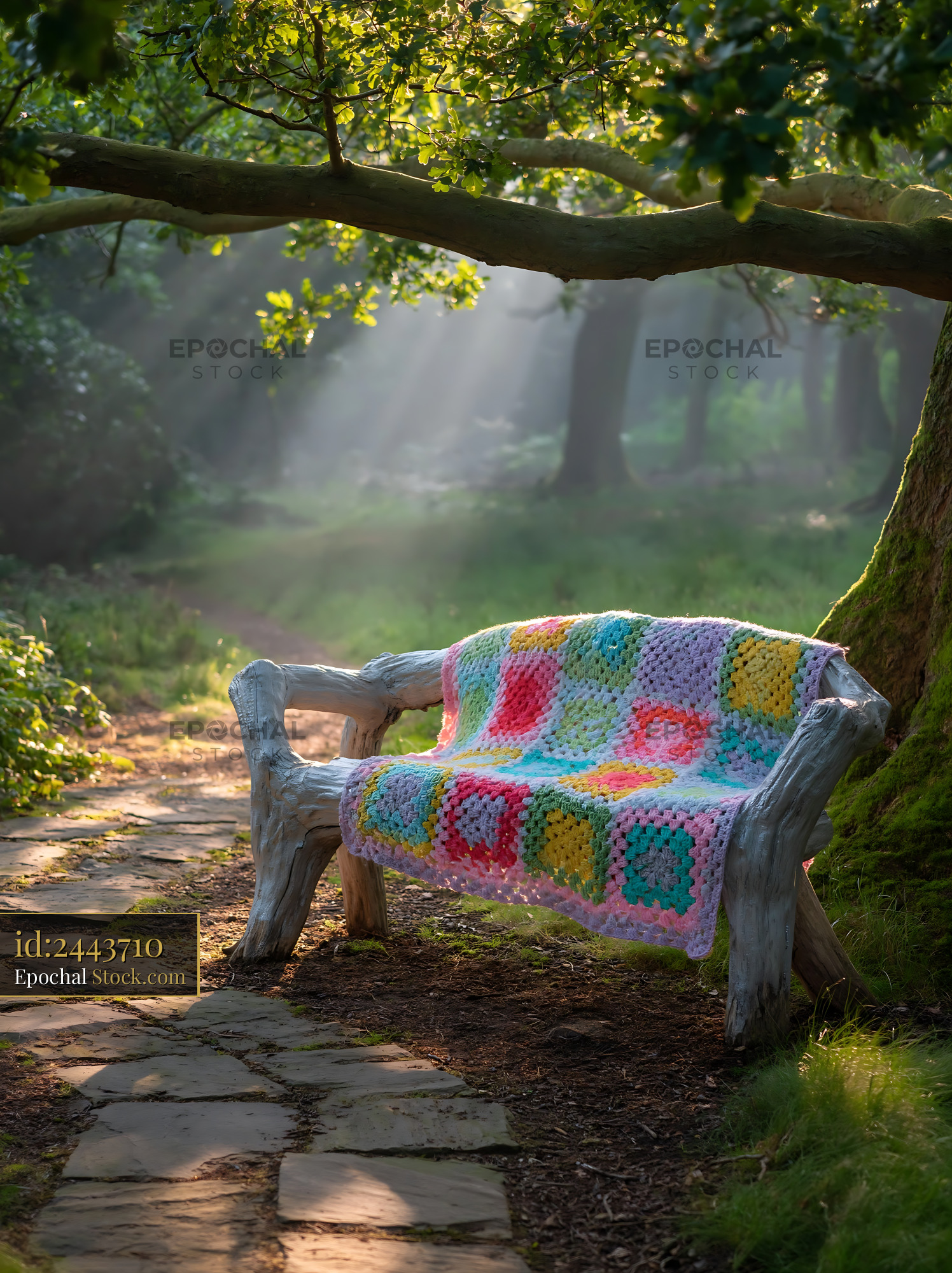 Colorful crochet blanket on rustic wooden bench in misty forest - stock photo