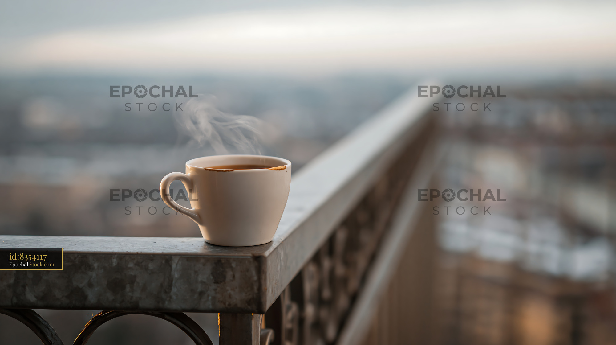 Steaming coffee cup on a balcony railing overlooking the city - stock photo