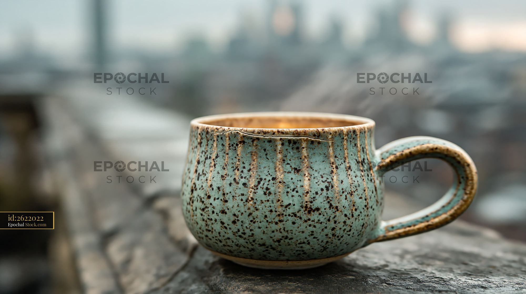 Steaming ceramic coffee cup on a balcony overlooking the city - stock photo