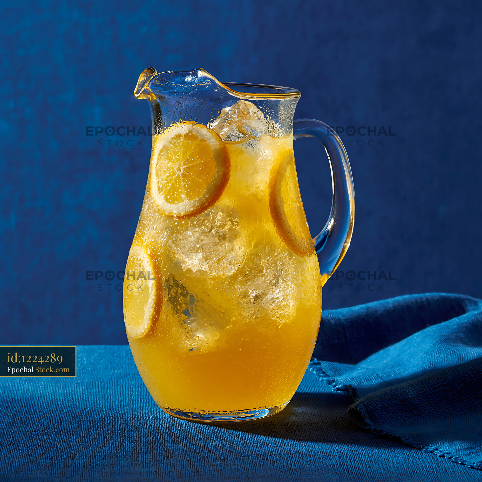 Chilled lemonade pitcher with ice cubes and citrus on blue background - stock photo
