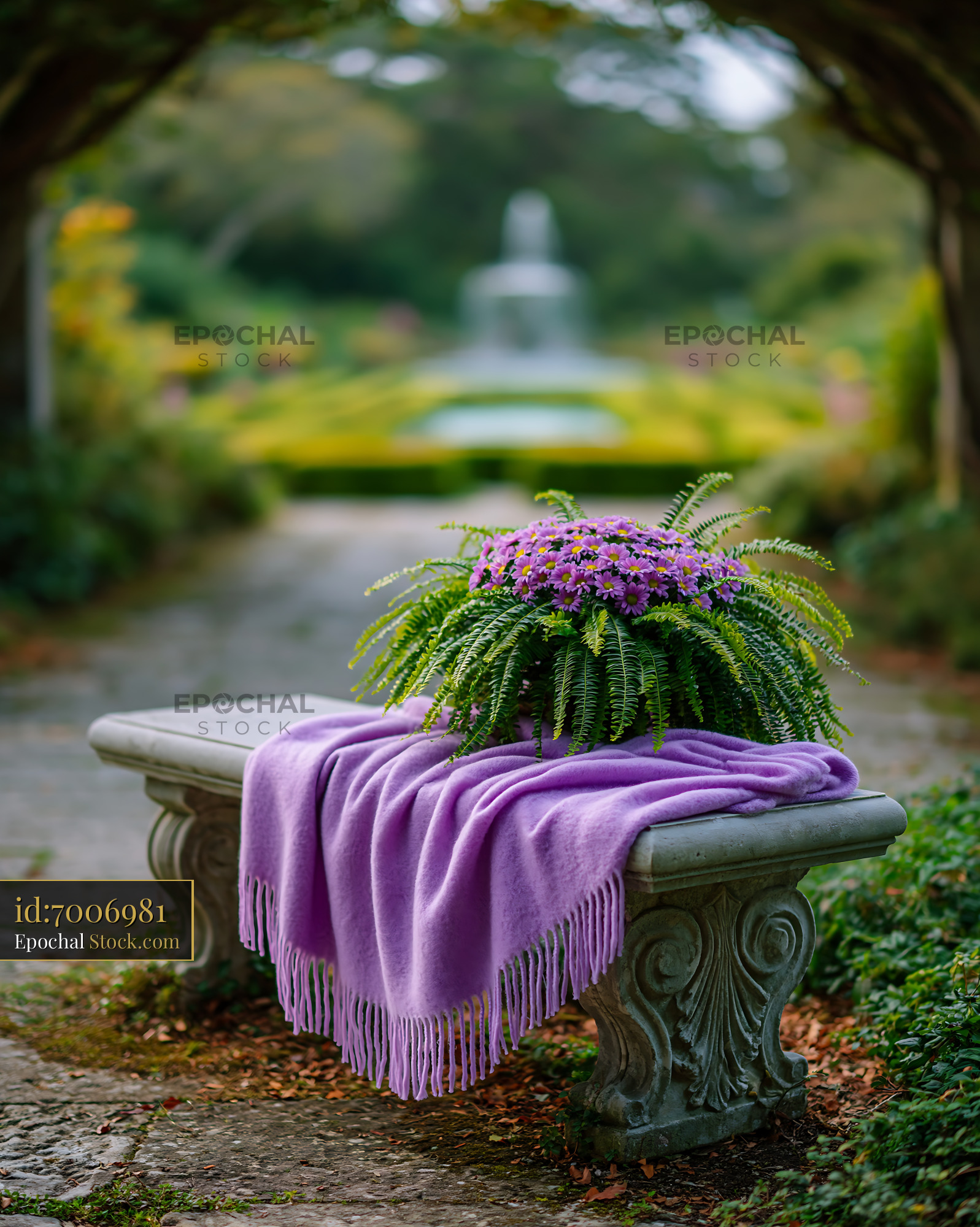 Purple blanket and flowers on a stone garden bench in a lush park - stock photo