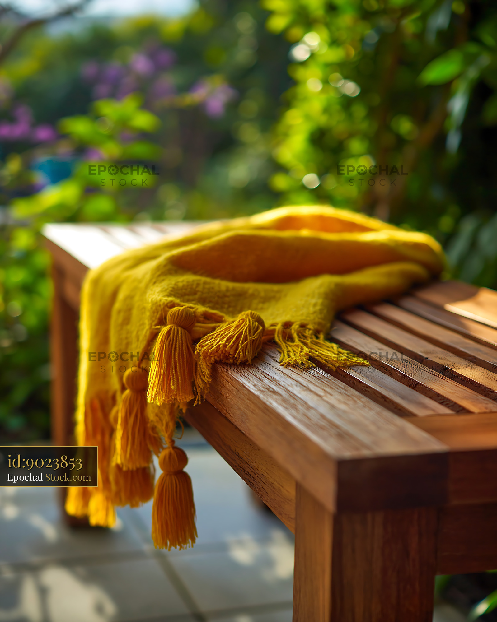 Yellow throw blanket with tassels on a wooden balcony bench - stock photo