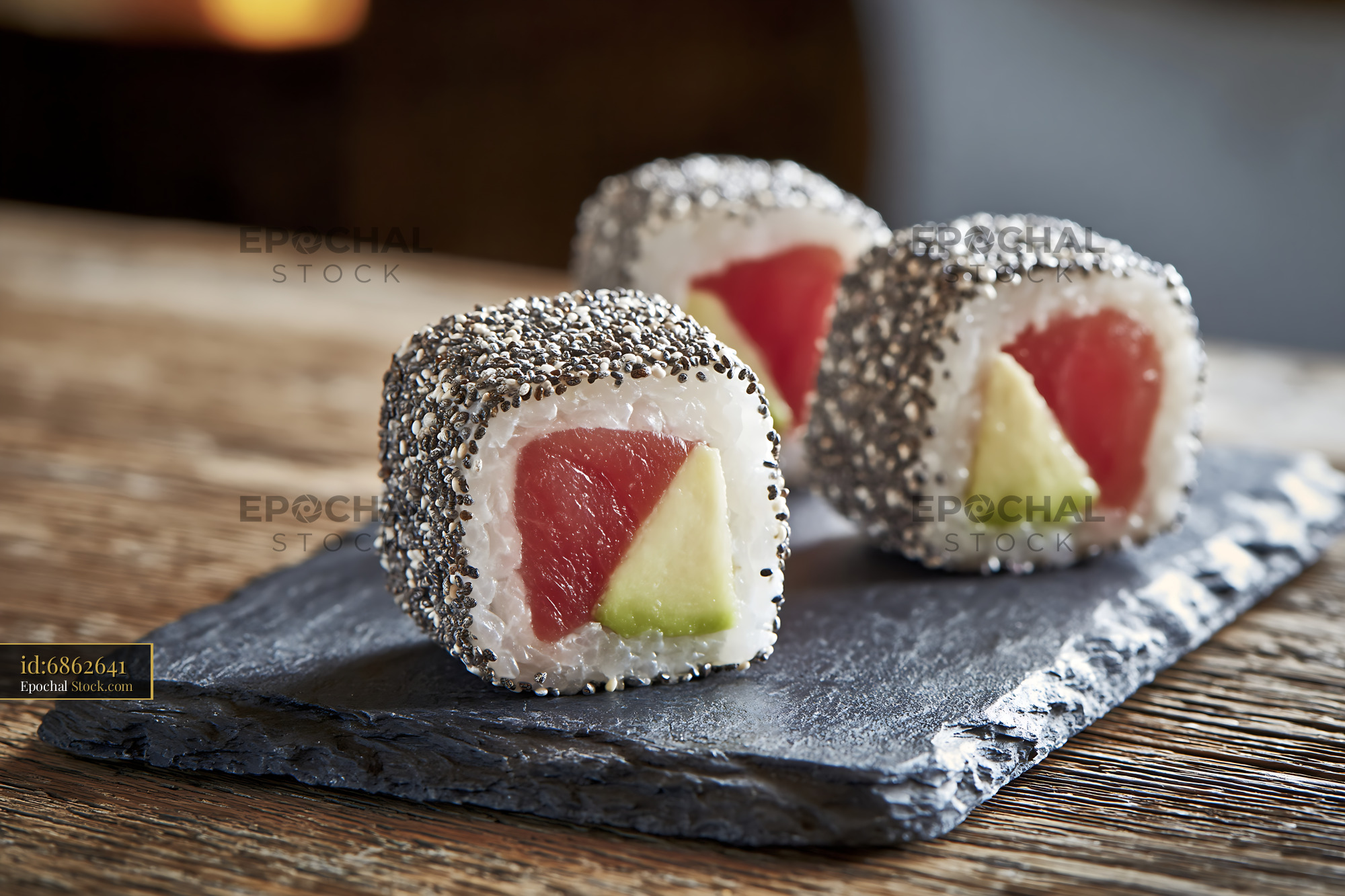 Three pieces of chia seed crusted sushi with tuna and avocado on slate - stock photo