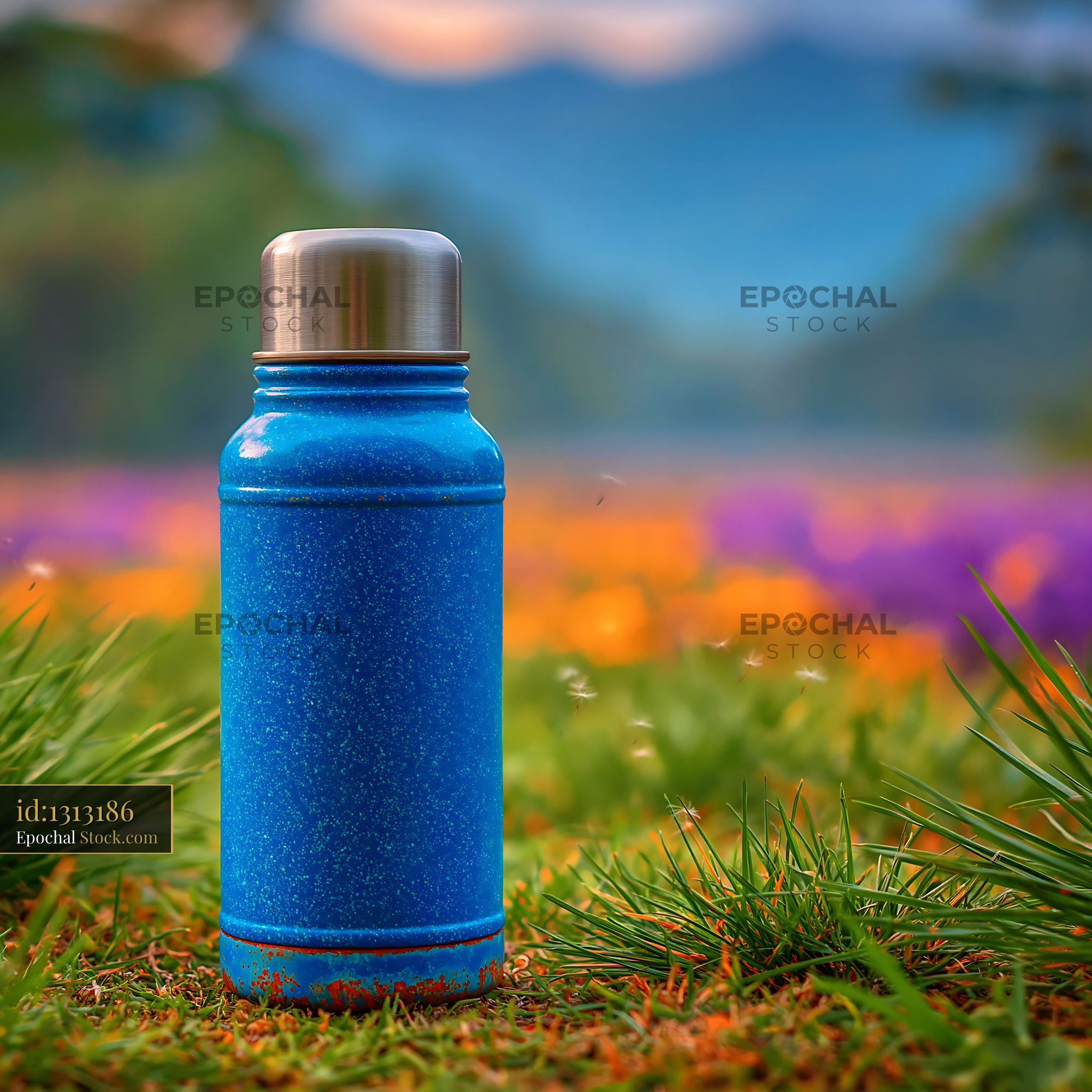 Blue vintage thermos on spring grass in a mountain flower meadow - stock photo