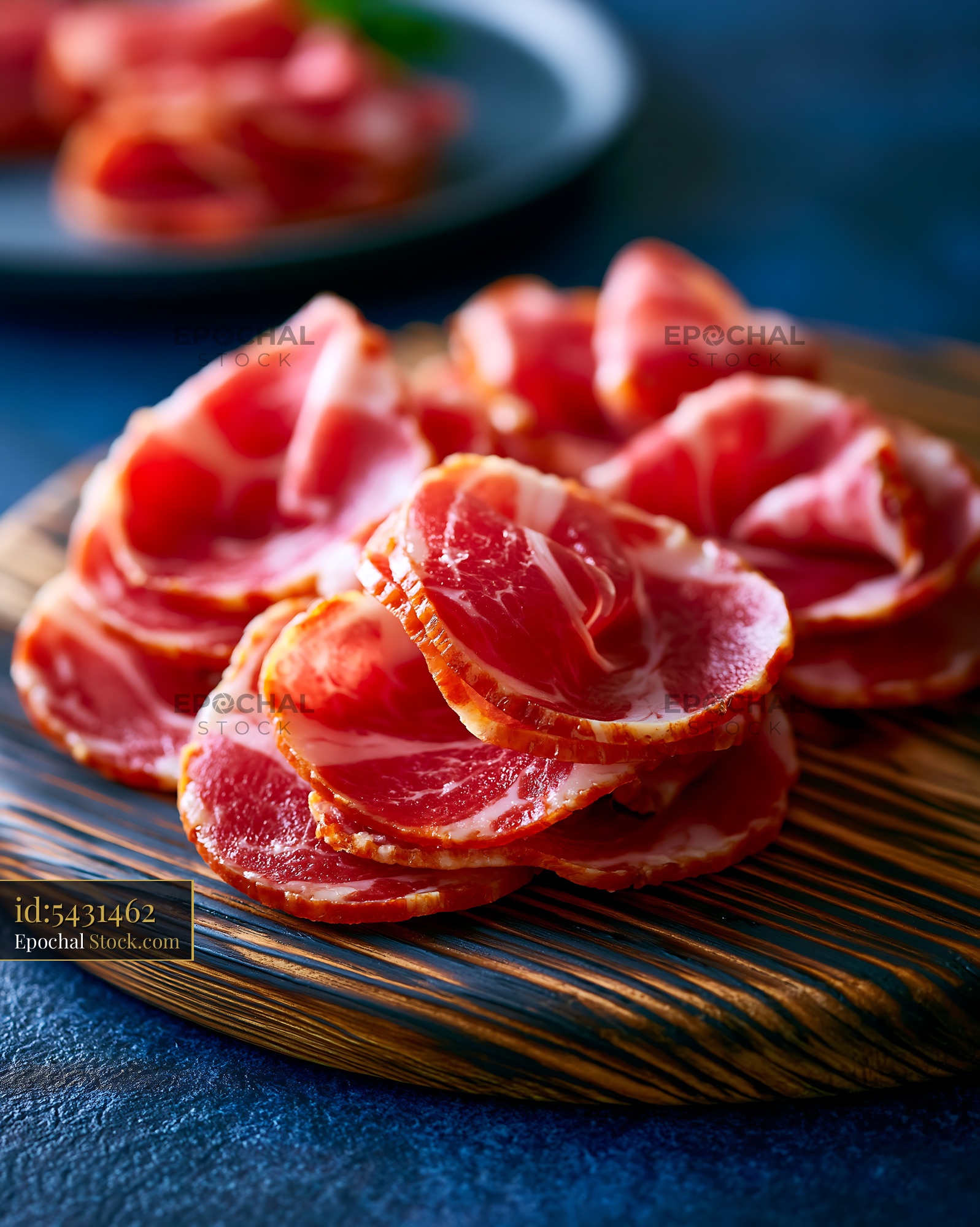 Thinly sliced culatello di zibello meat on a rustic wooden board - stock photo