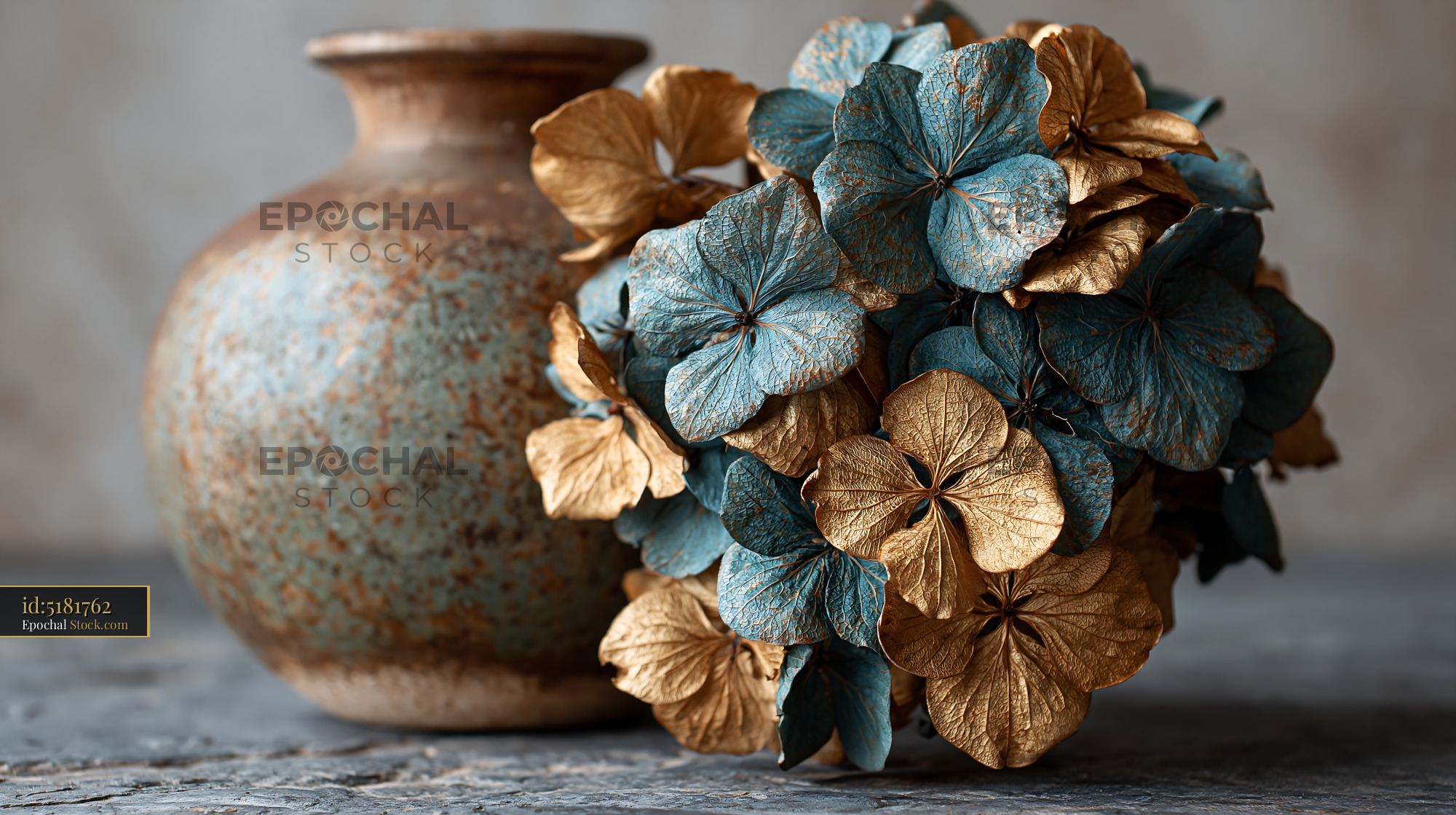 Dry hydrangea bouquet on a table next to a rustic ceramic vase - stock photo