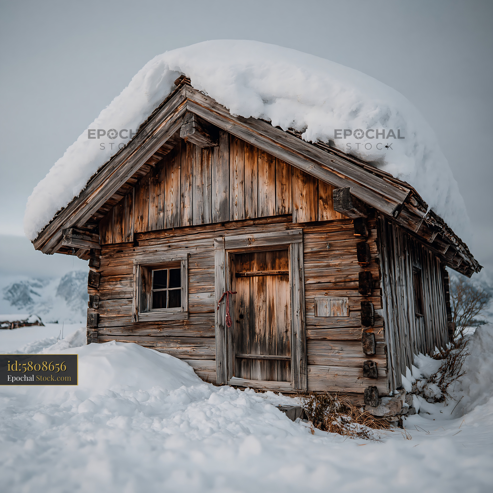 Old rustic wooden cabin covered in thick snow in the mountains - stock photo