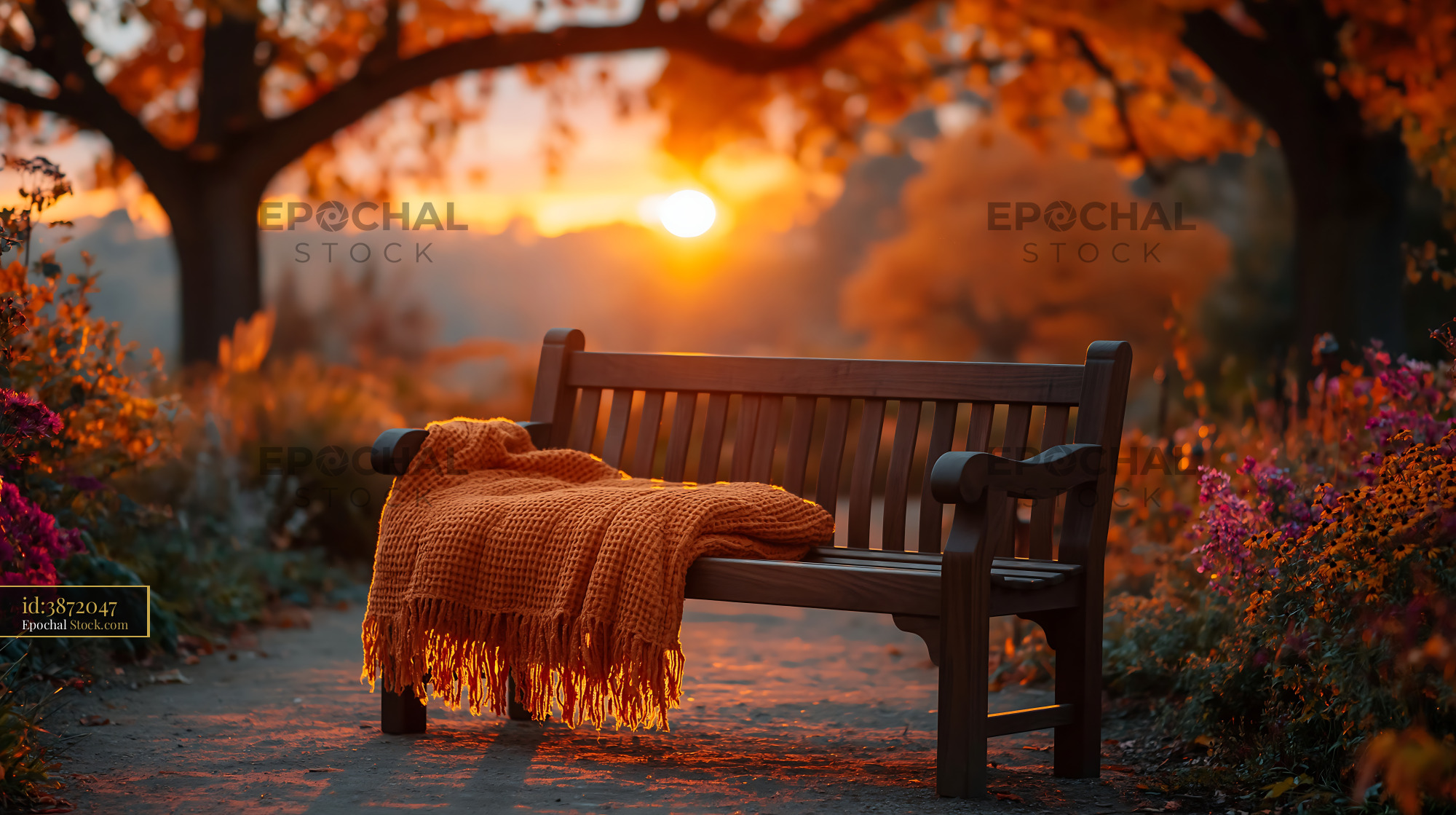Patterned blanket on a wooden park seat at sunset in autumn - stock photo