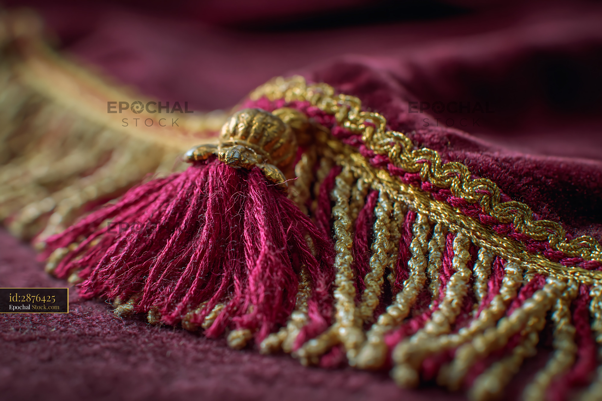 Red velvet stage curtain with ornate gold fringe and decorative tassel