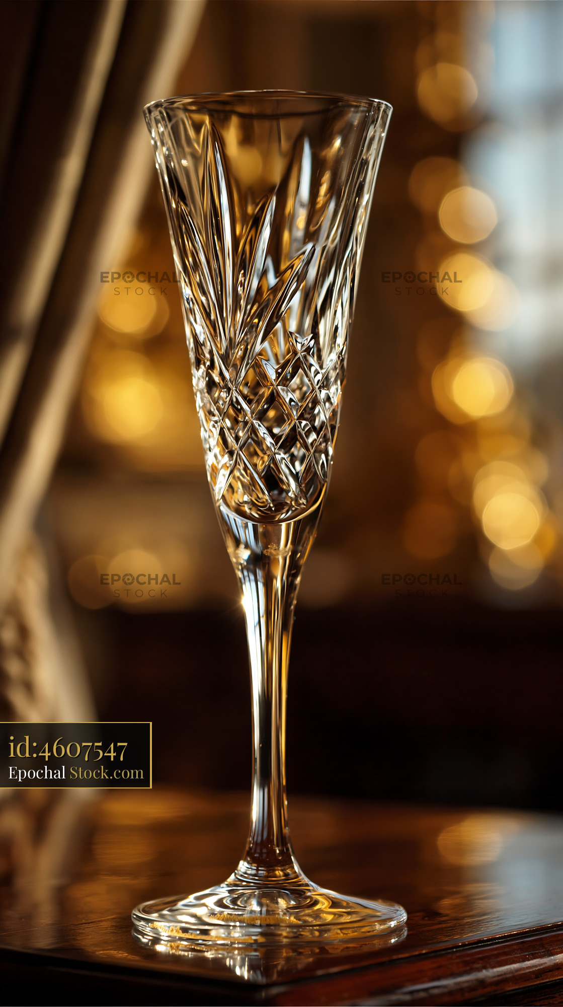 Empty crystal champagne flute on a wooden table with golden bokeh - stock photo