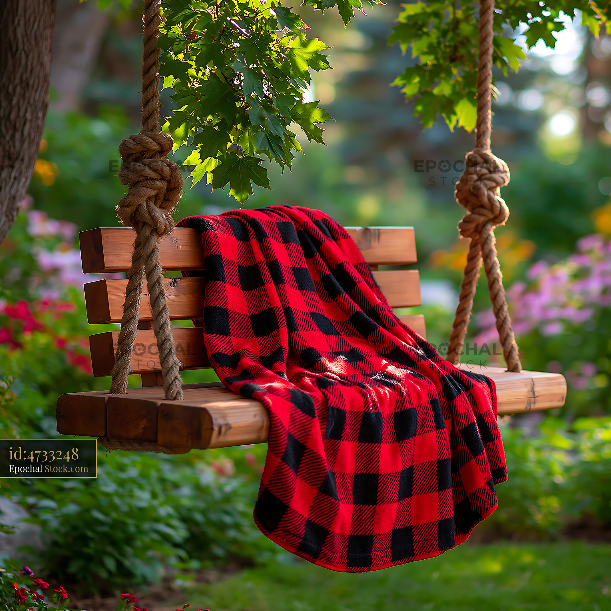 Wooden garden swing with red checkered blanket in a sunny backyard - stock photo
