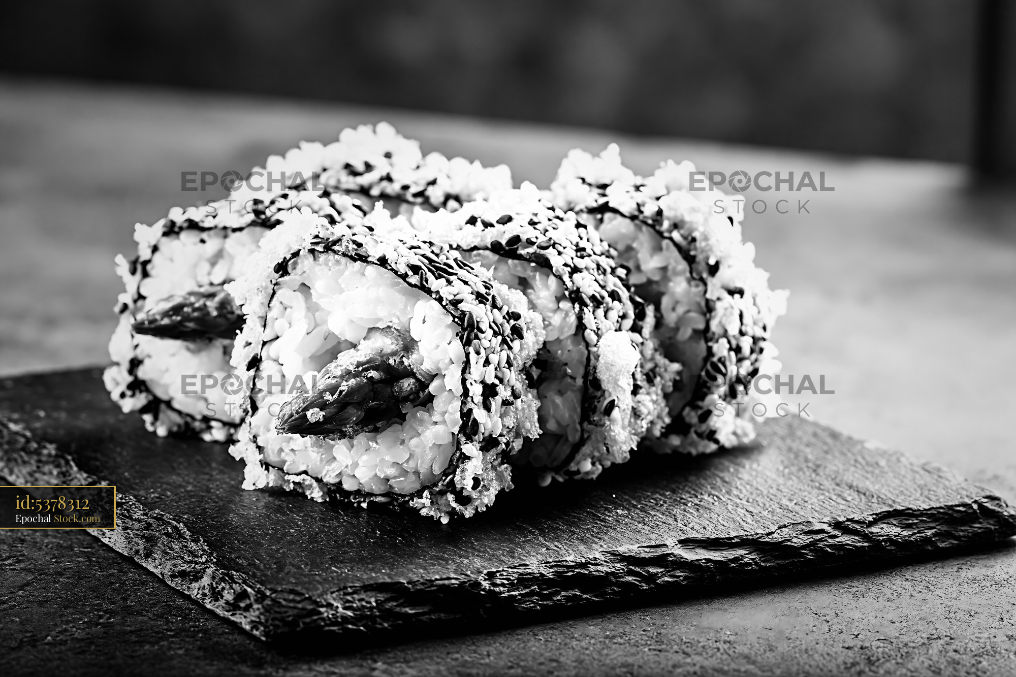 Tempura asparagus sushi rolls served on a slate board in black and whi - stock photo