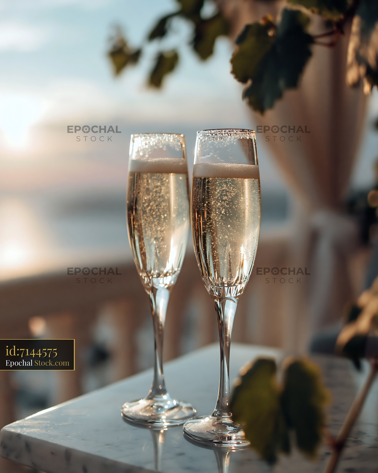 Two glasses of sparkling wine on a terrace at sunset - stock photo