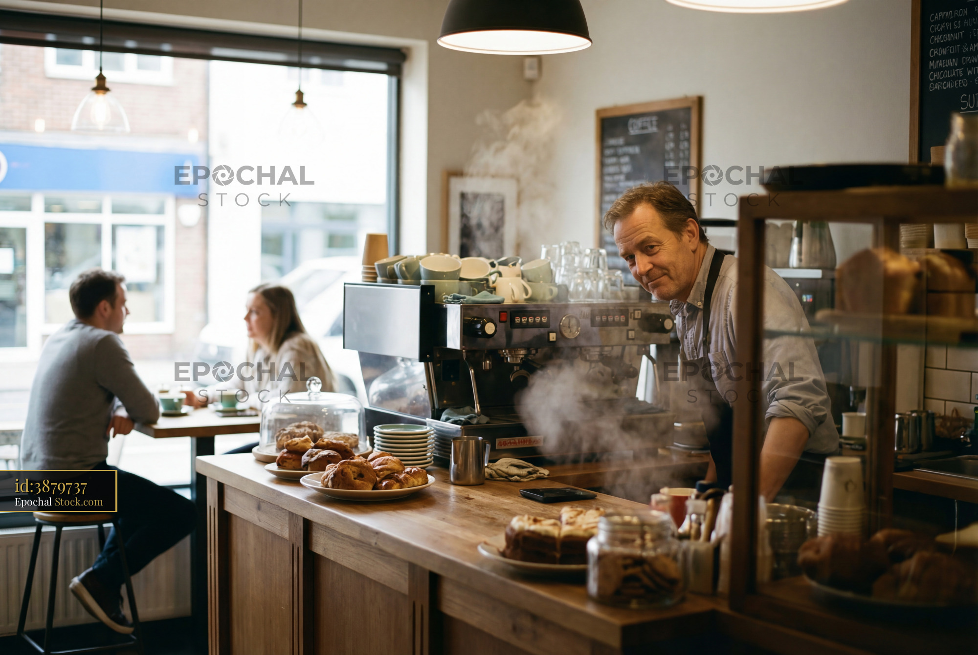Barista serves coffee and pastries in busy cafe setting - stock photo