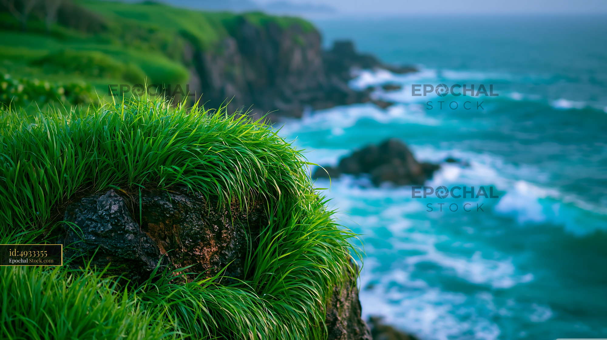 Vibrant green grass on a rocky sea cliff overlooking turquoise waves - stock photo