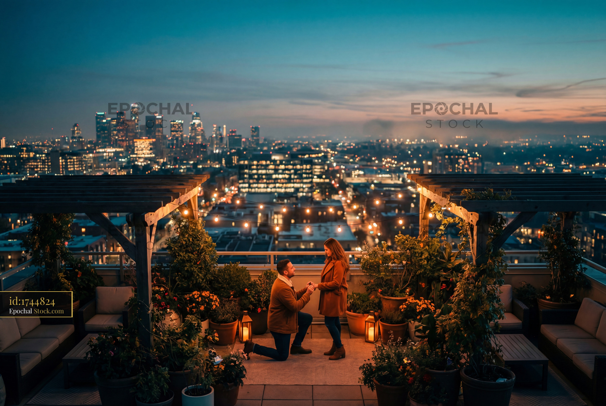 Couple enjoys proposal on rooftop with city skyline at sunset - stock photo