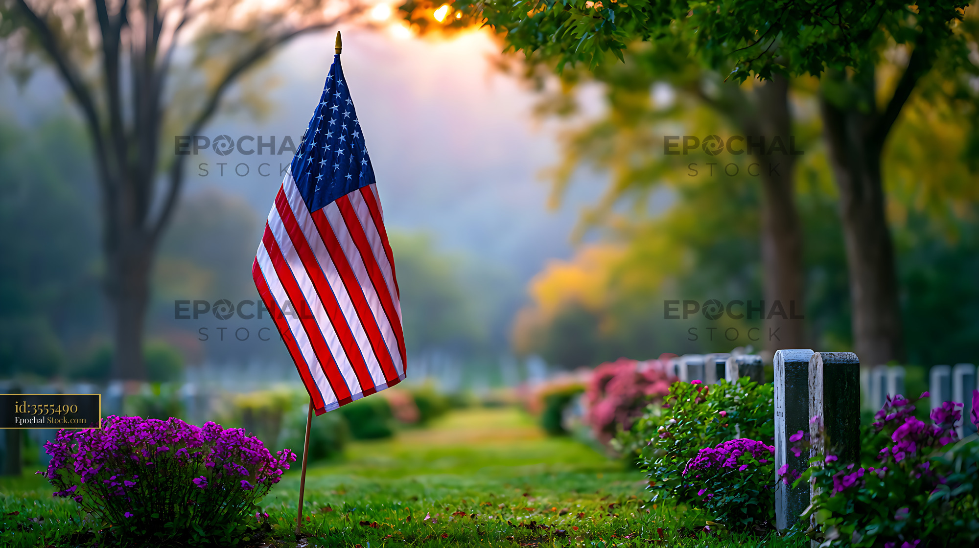 American flag in a military cemetery at golden hour with flowers - stock photo