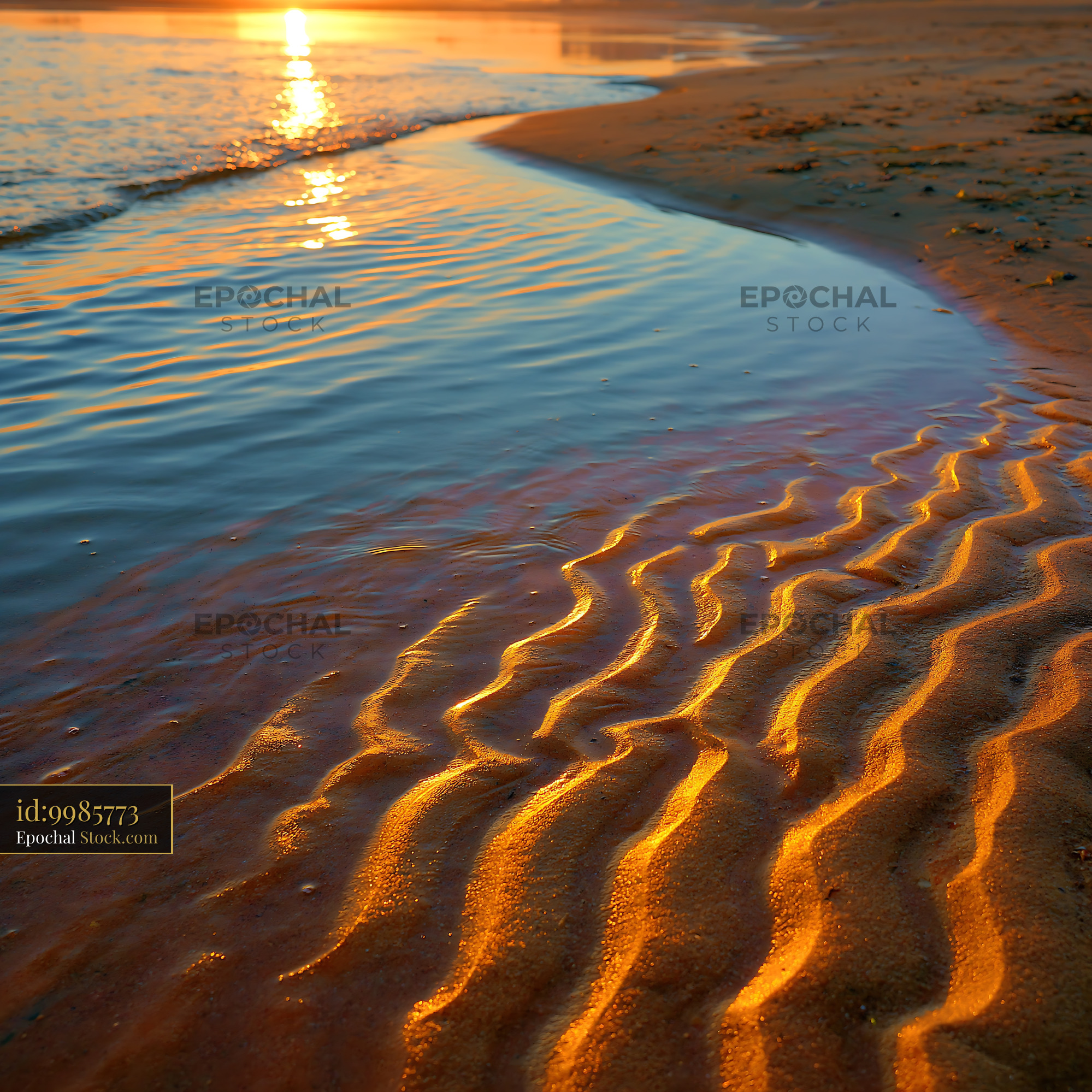 Golden sunset light reflecting on rippled sand patterns at the beach - stock photo