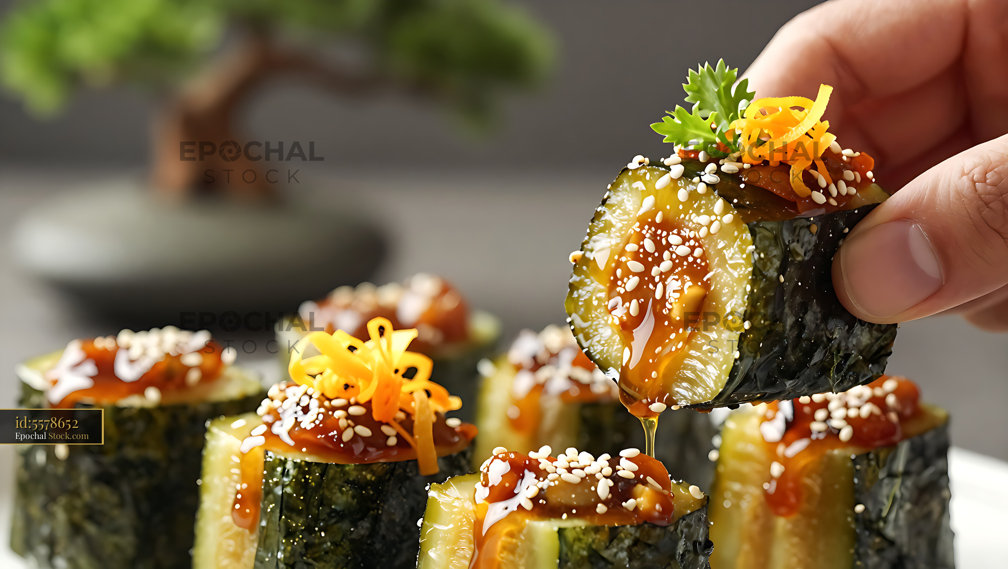 Hand holding a kanpyo maki sushi roll with dripping sauce - stock photo