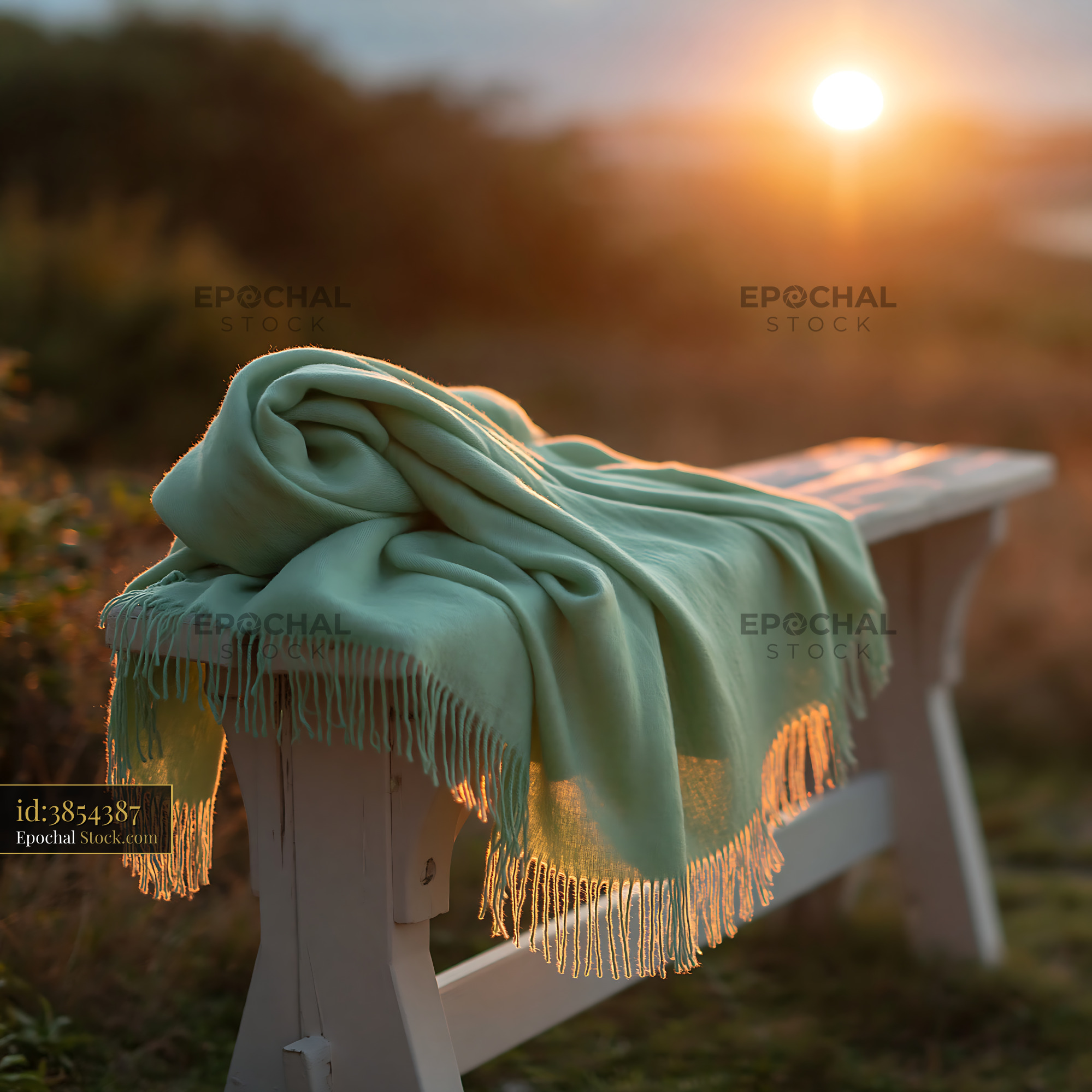 Light green cashmere throw on a white wooden bench at sunset - stock photo