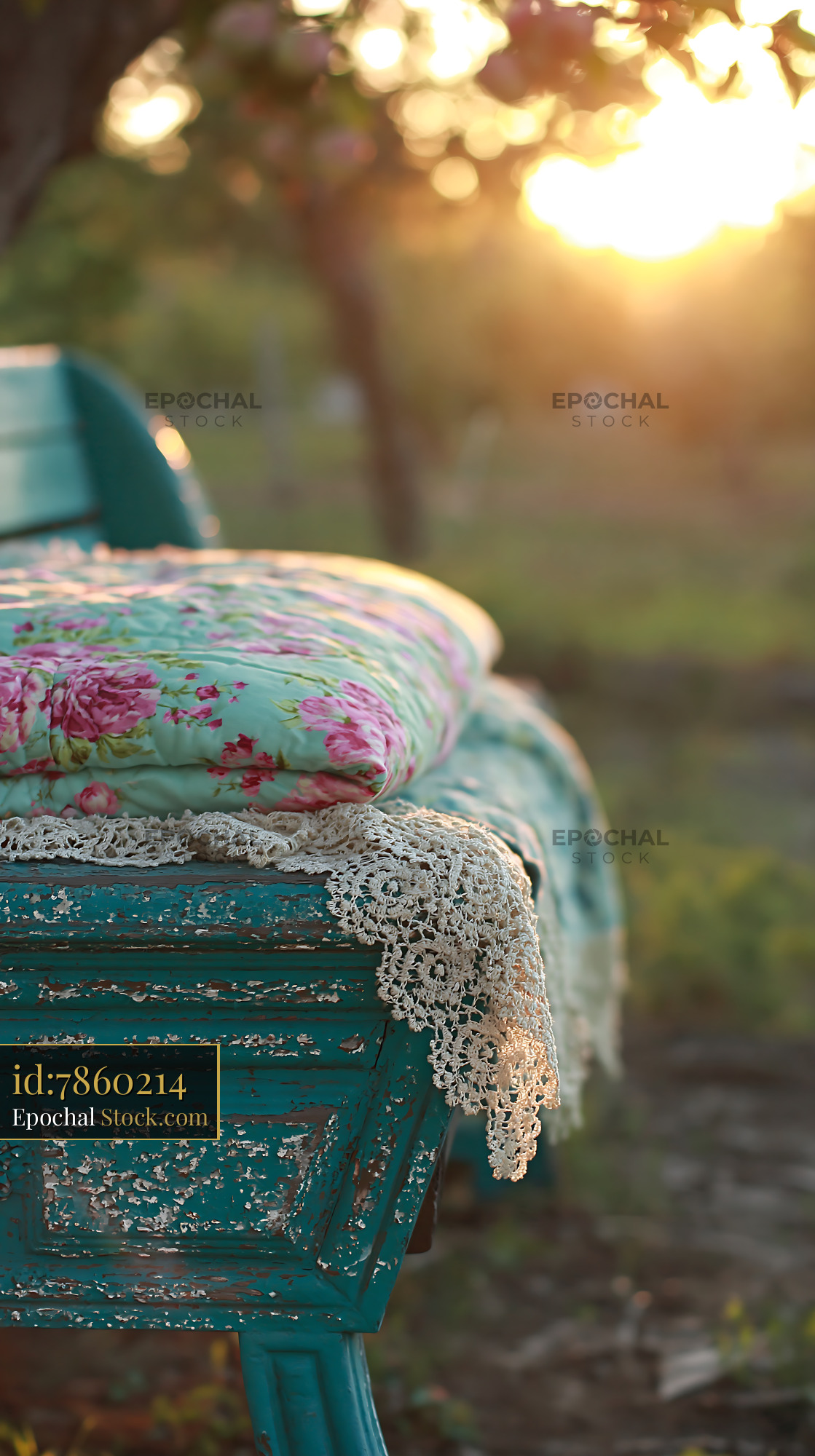 Vintage turquoise wooden bench with floral quilt and lace at sunset - stock photo