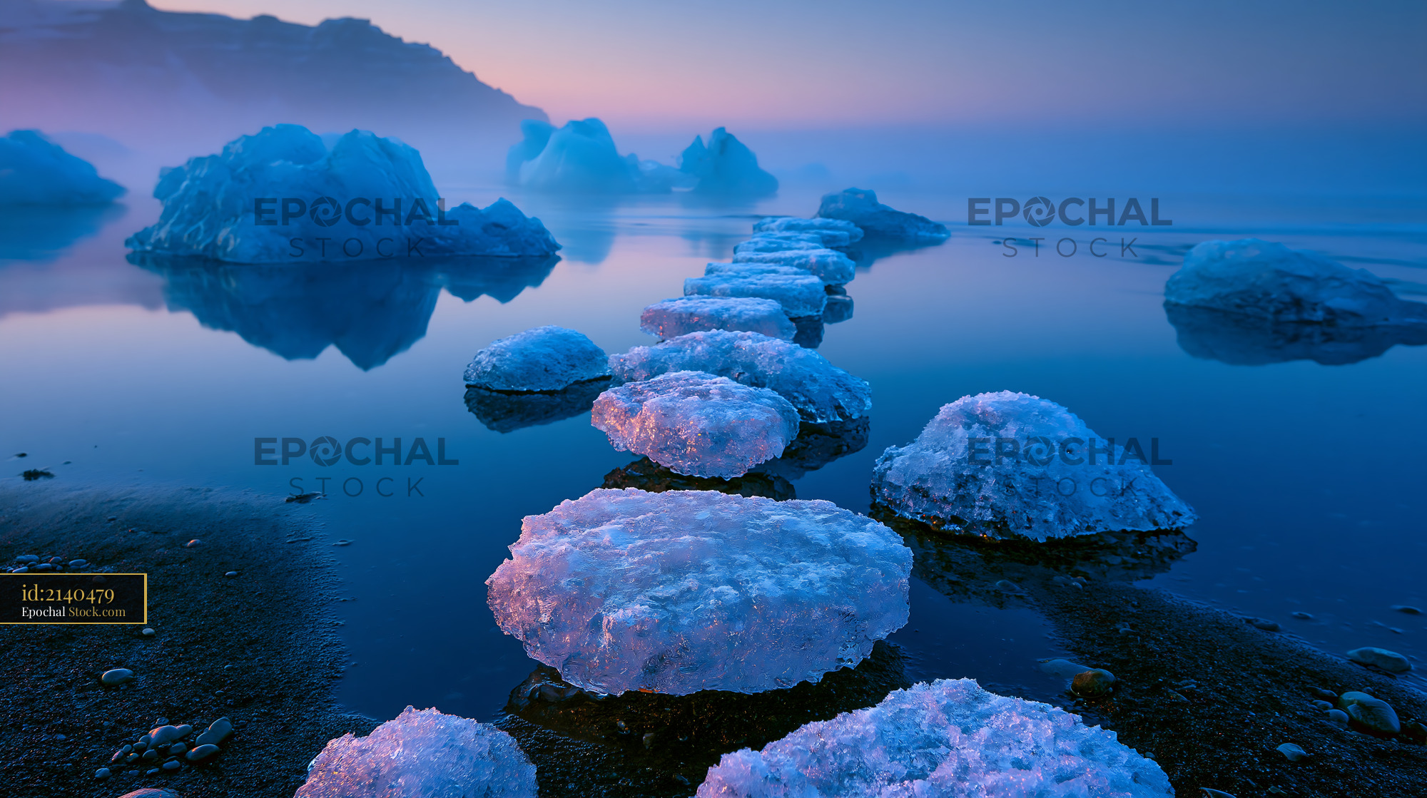 Glacial ice chunks forming stepping stones on a misty beach at dawn - stock photo