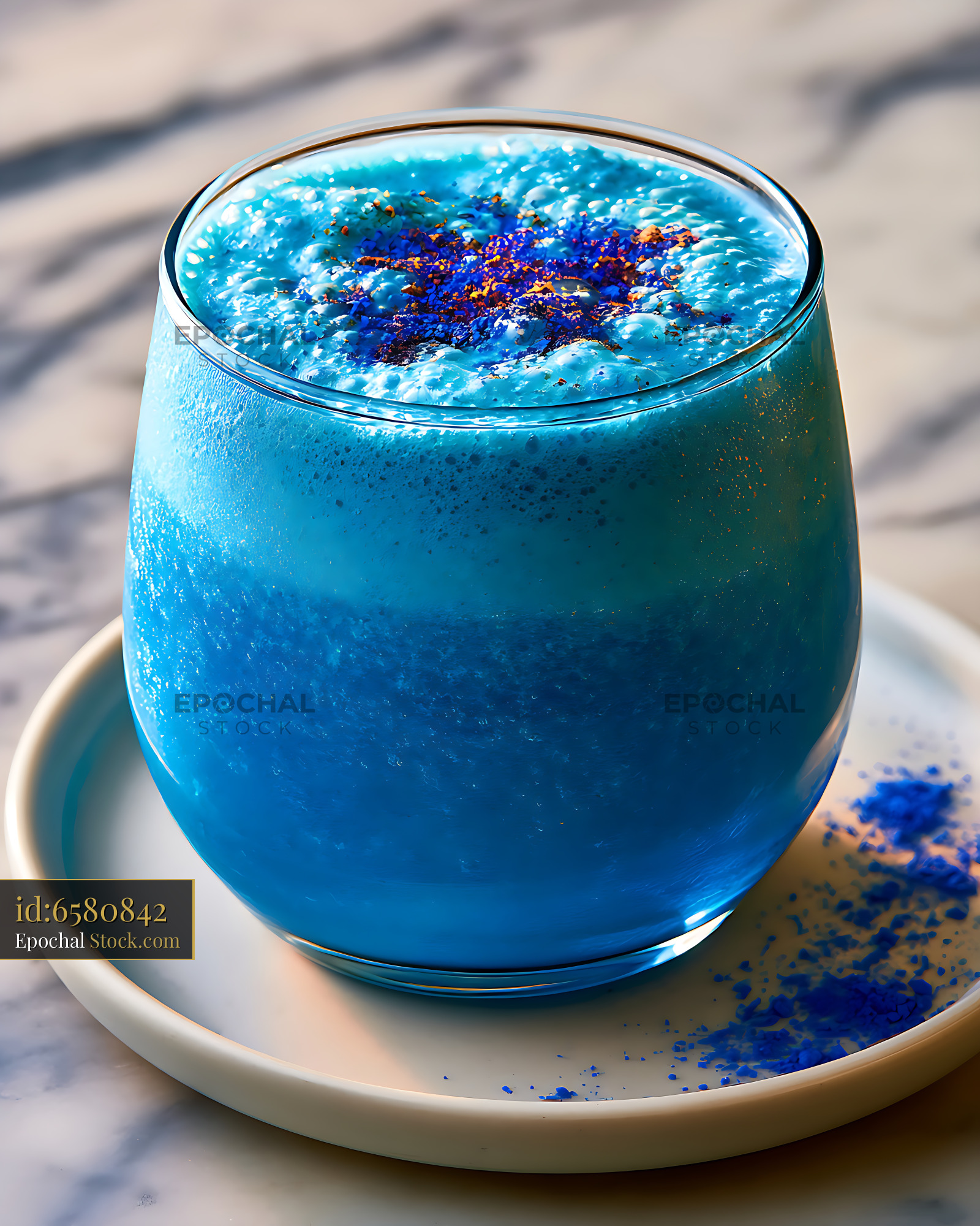 Vibrant blue spirulina smoothie with foam and toppings on marble table - stock photo