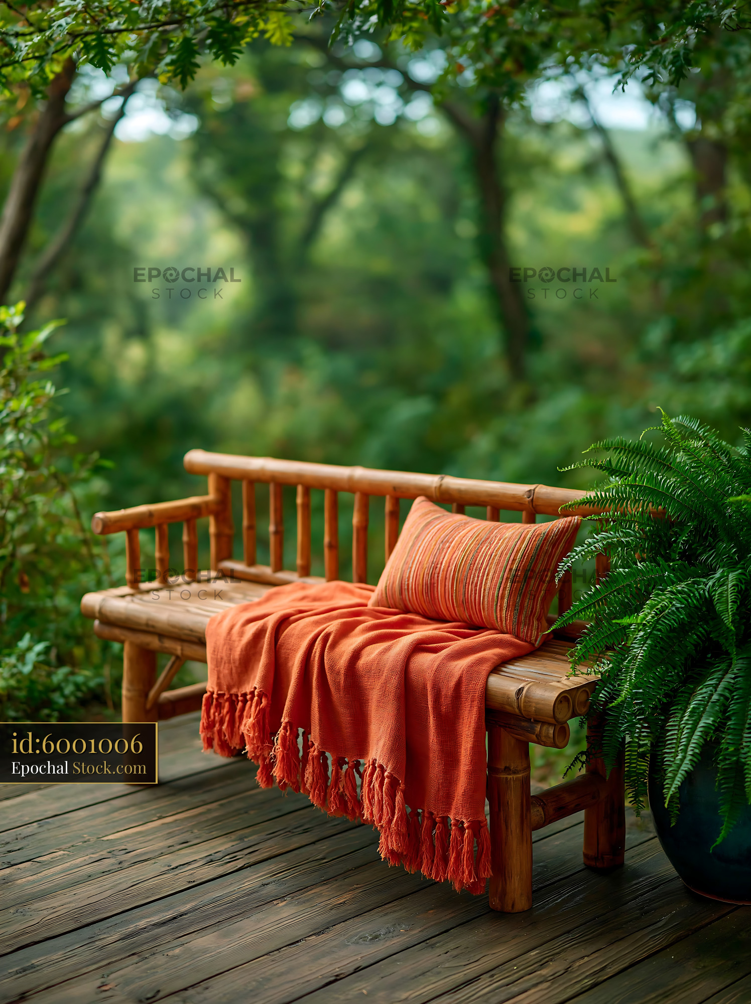 Bamboo bench with orange blanket and striped throw on garden deck - stock photo