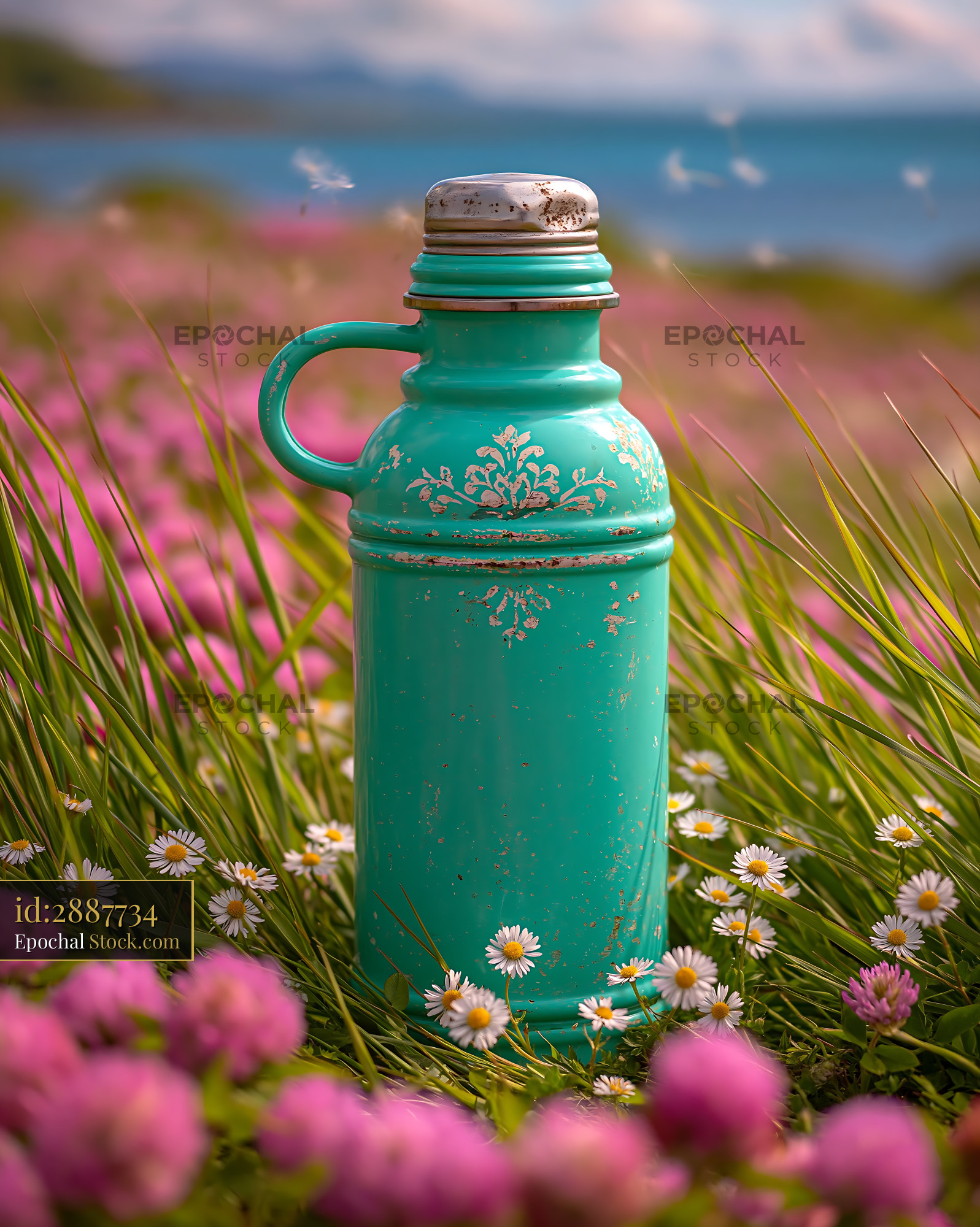 Vintage turquoise thermos standing in a field of spring grass