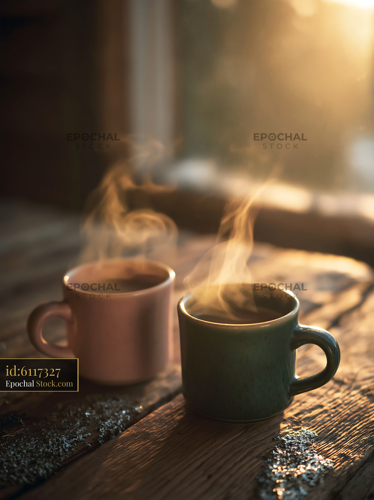 Two steaming coffee mugs on a rustic wooden table in golden morning li - stock photo